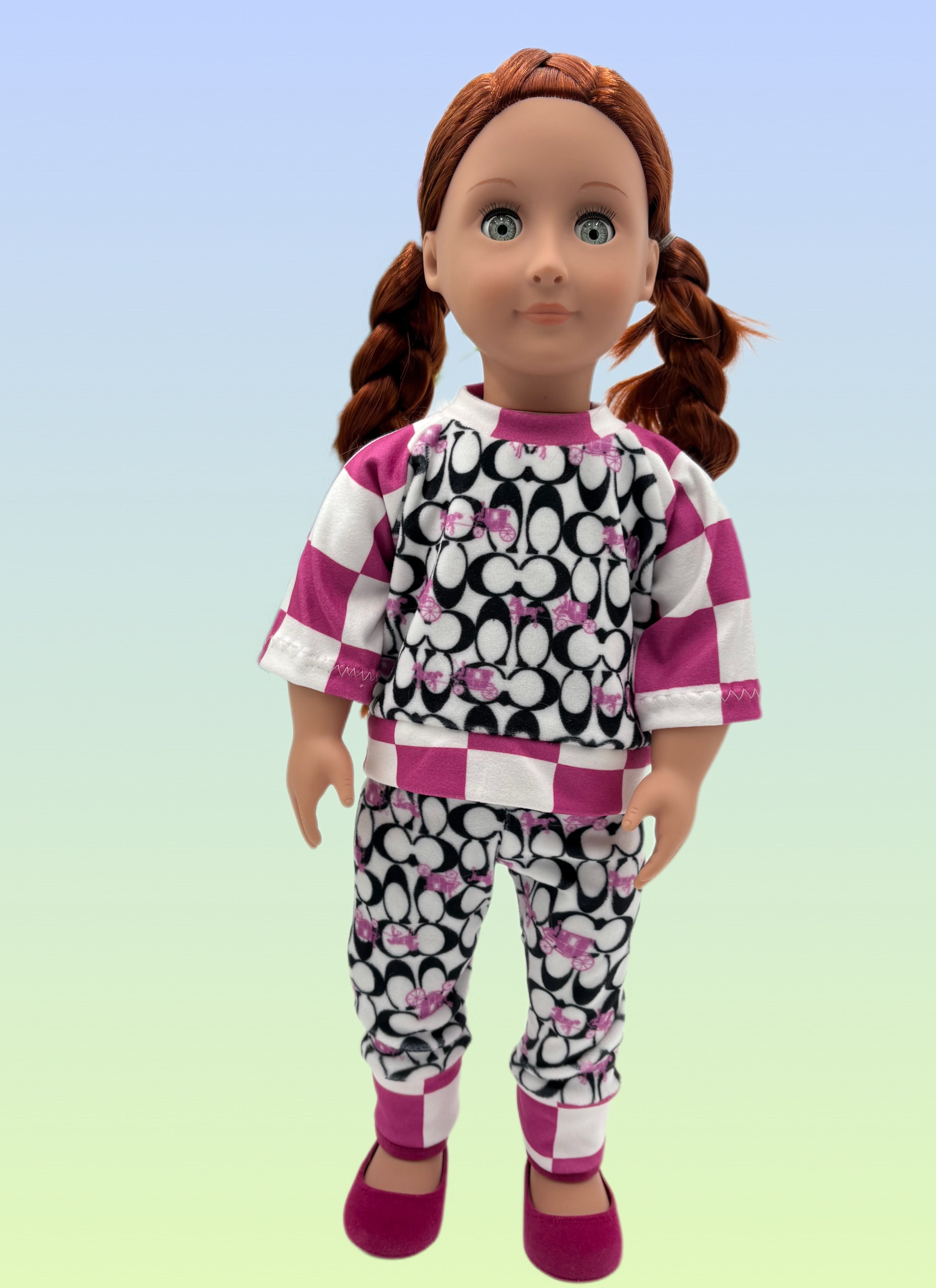 18-inch doll wearing a handmade pink and black patterned pajama set with checkered accents and matching pants.