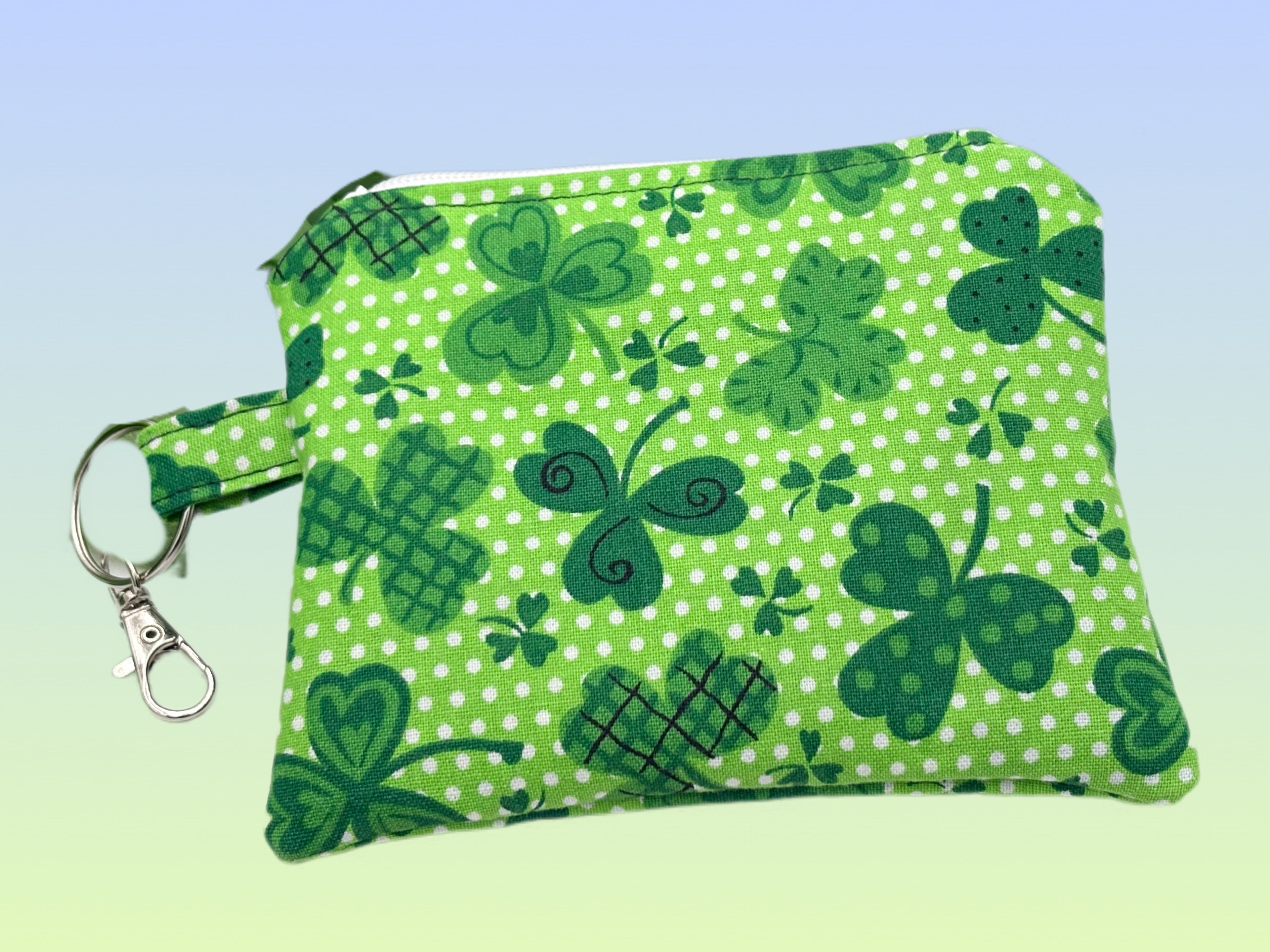 Handmade green shamrock print coin purse keychain with zipper closure and metal clip.