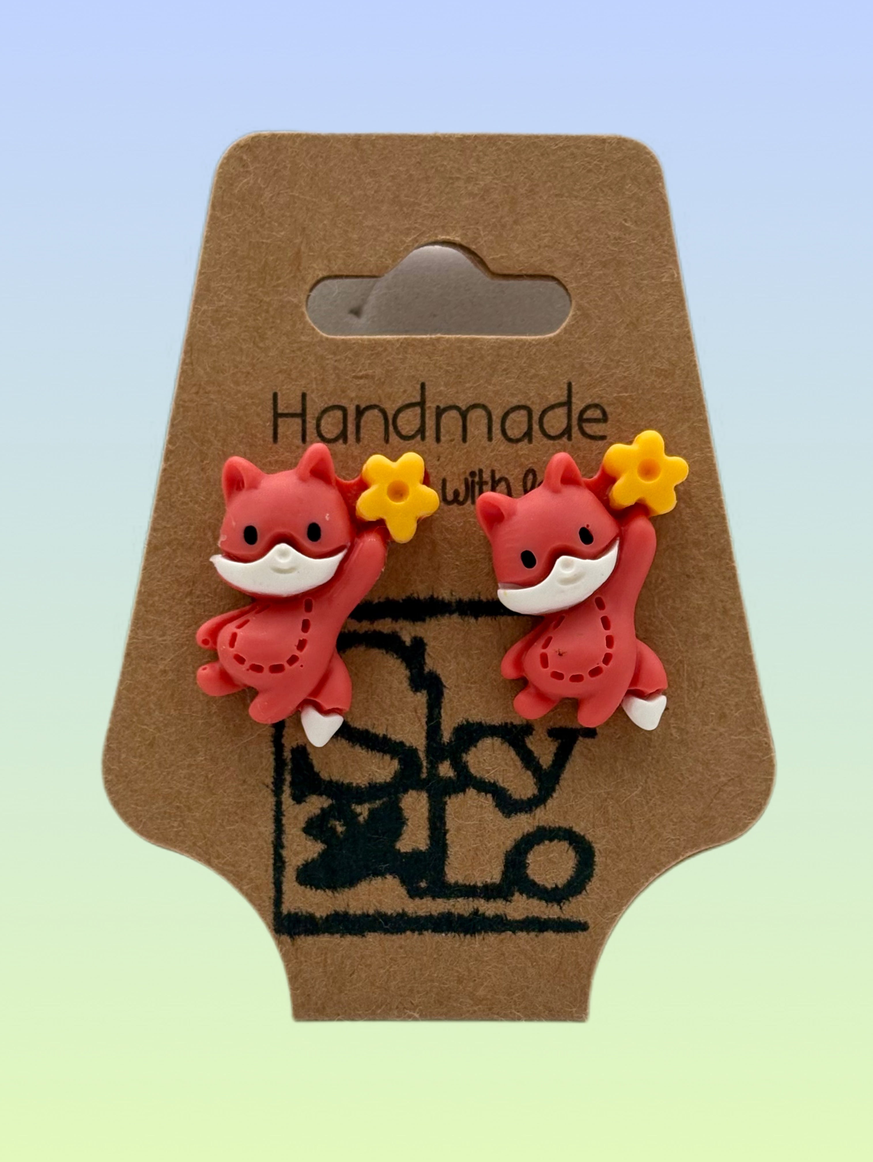 Cute handmade red fox stud earrings with yellow flower accents on a handmade jewelry display card.