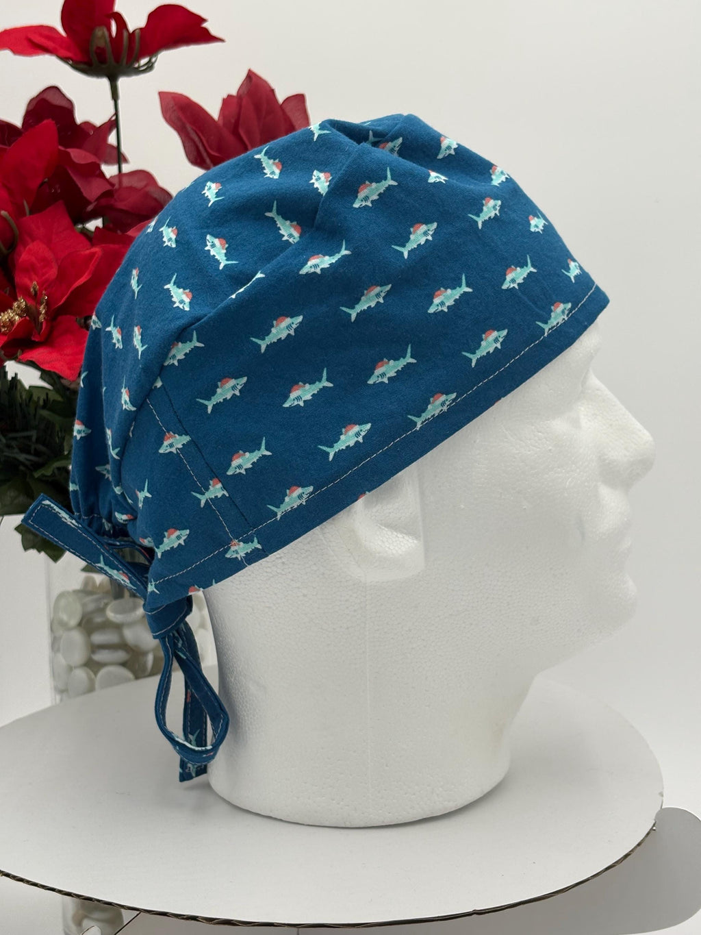 Blue scrub cap with shark pattern on a mannequin head against a white background