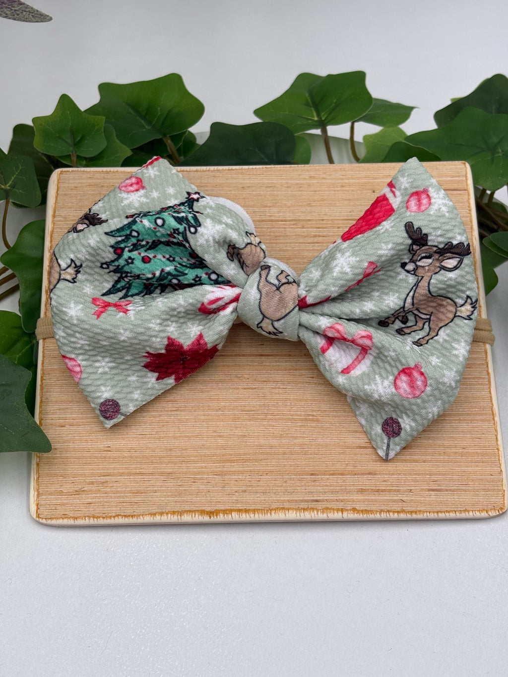 Nylon Headband with a decorative christmas themed big bow on a wooden plank against a white background
