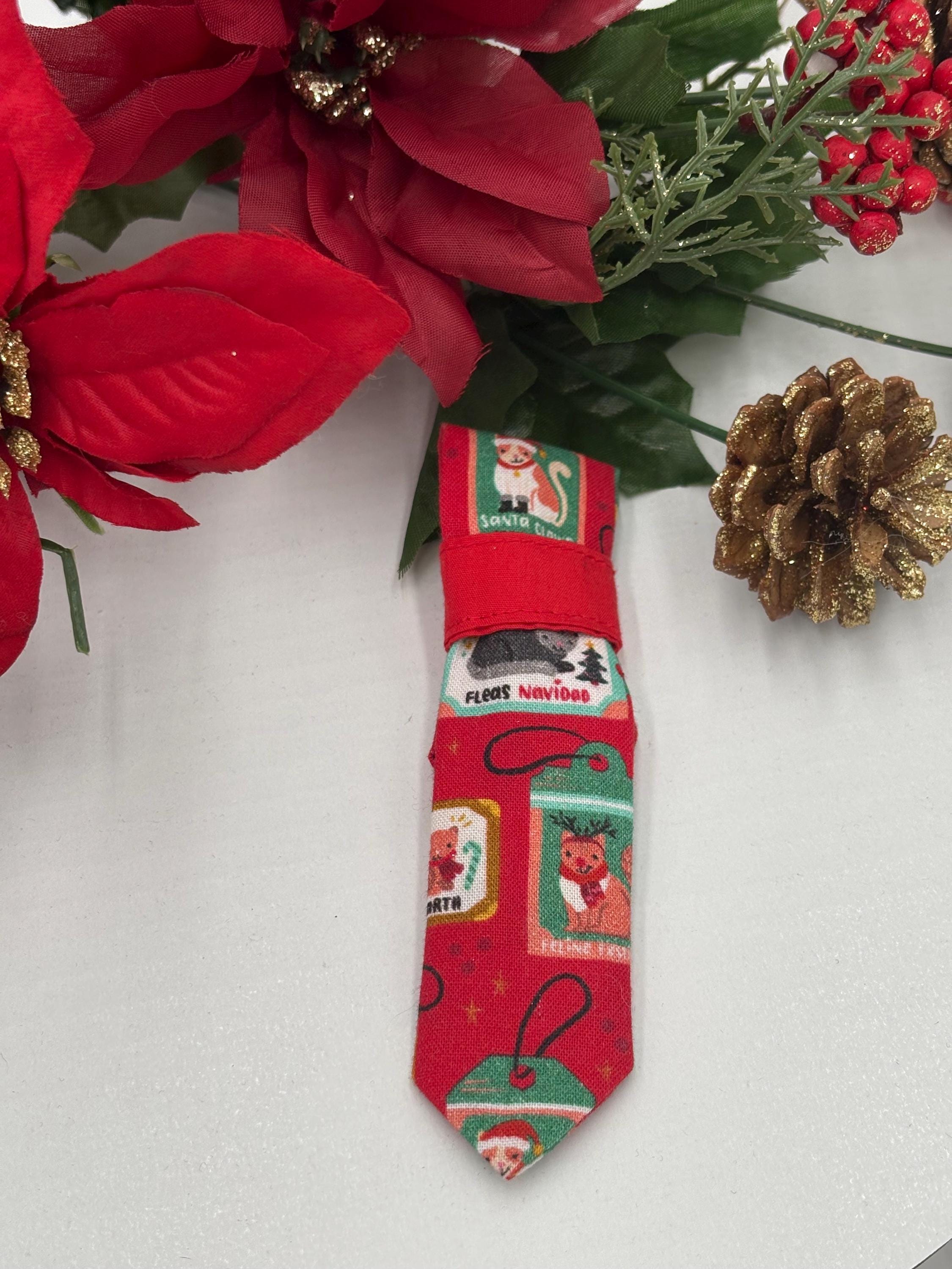 Red Christmas-themed over the collar necktie with festive designs on a white background with poinsettias and a pine cone.