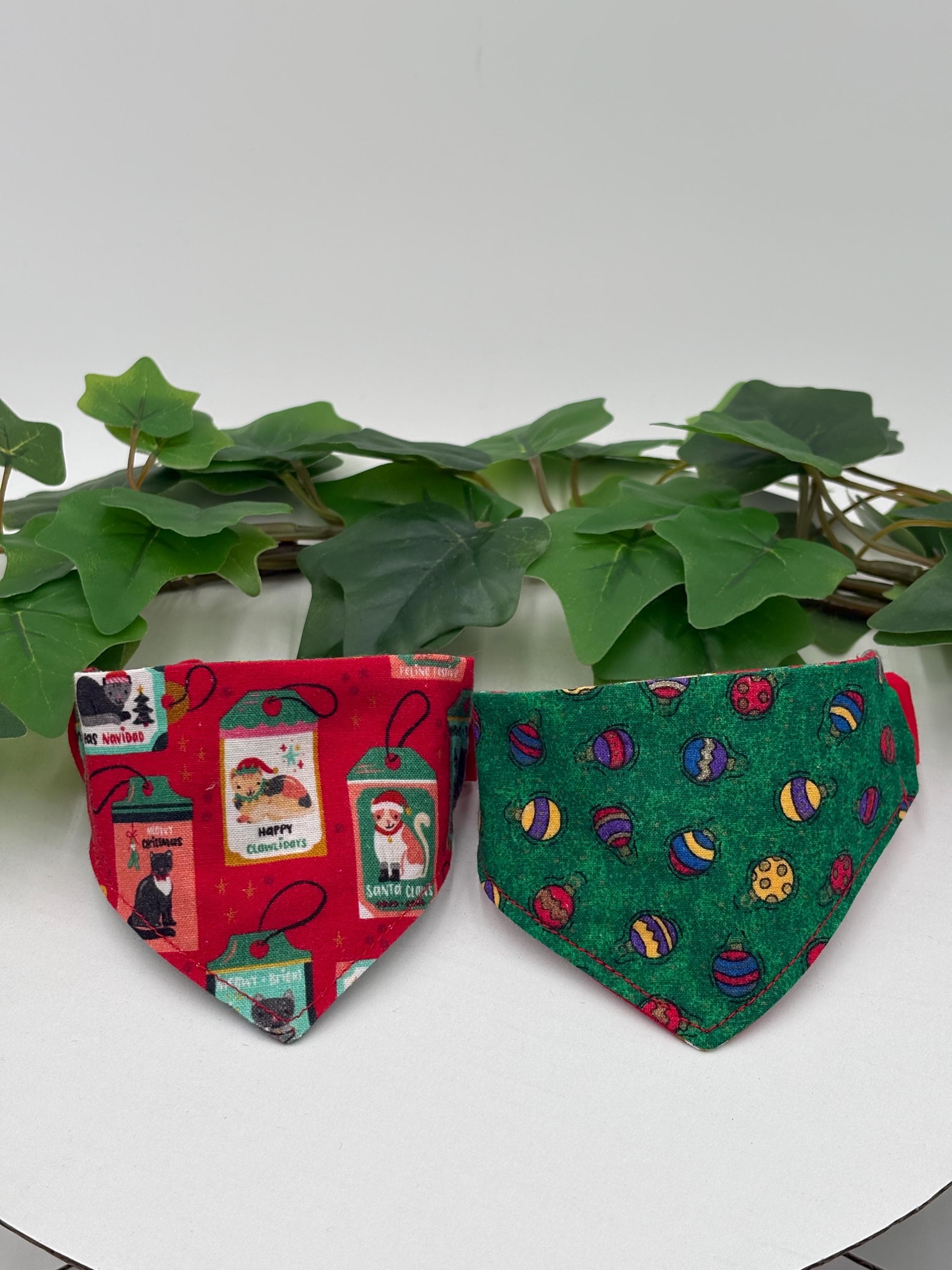 Two colorful scrunchie pet bandanas on a white surface with green leaves in the background