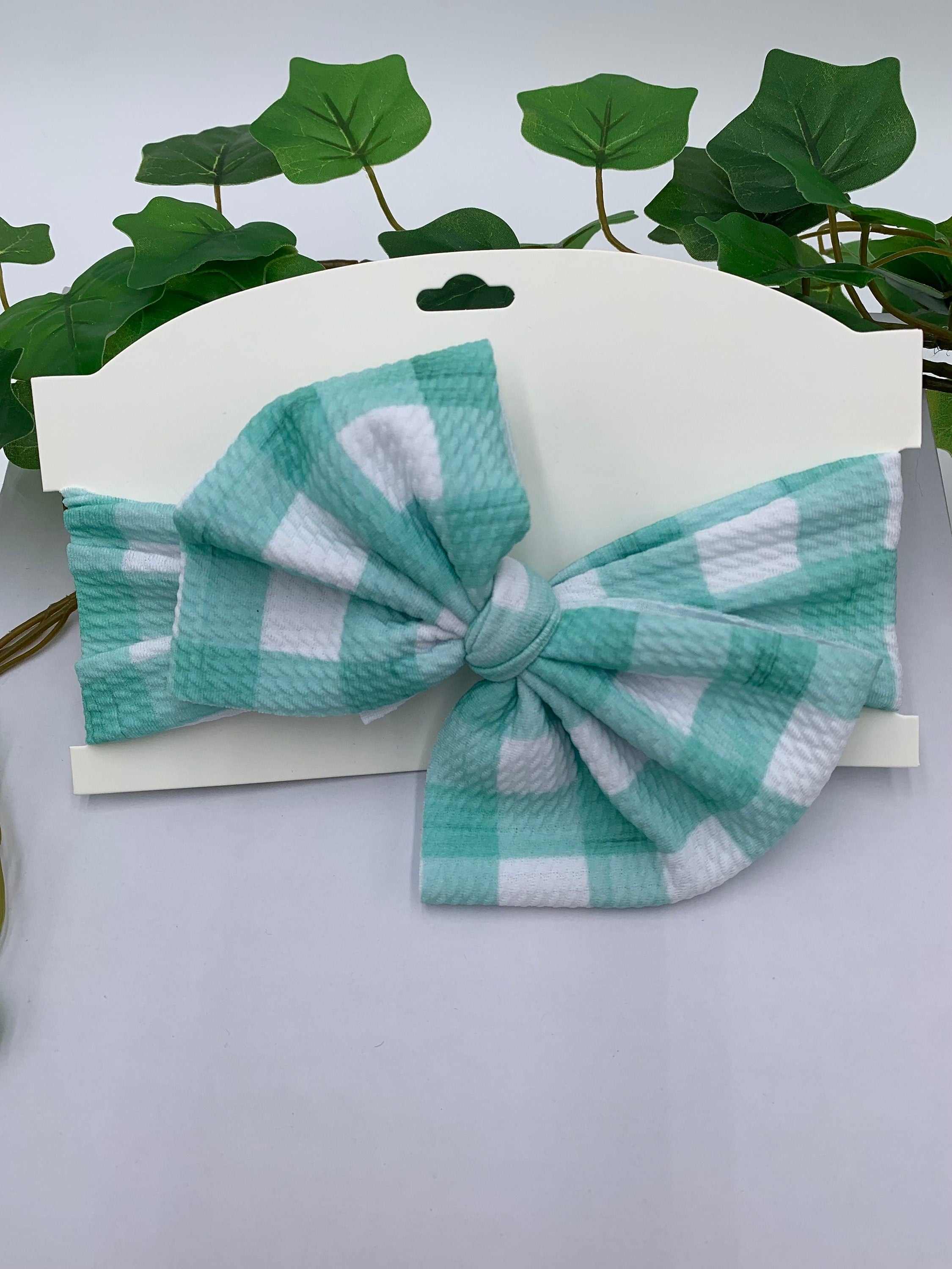 Blue and white checkered bow on a white background with green leaves in the background