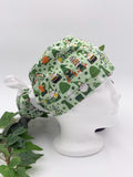 Green gnome scrub cap on a mannequin head against a white background with plant