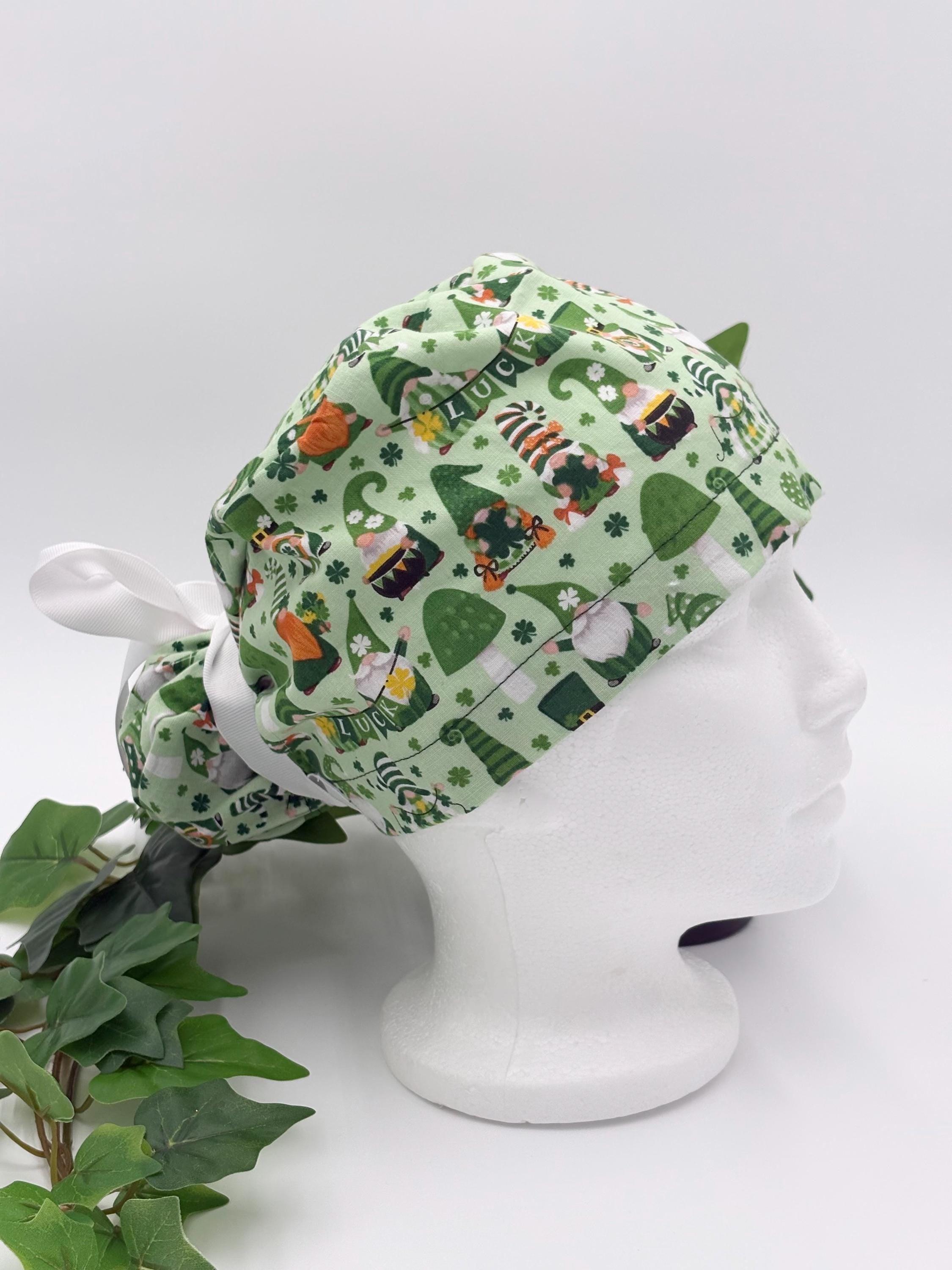 Green gnome scrub cap on a mannequin head against a white background with plant