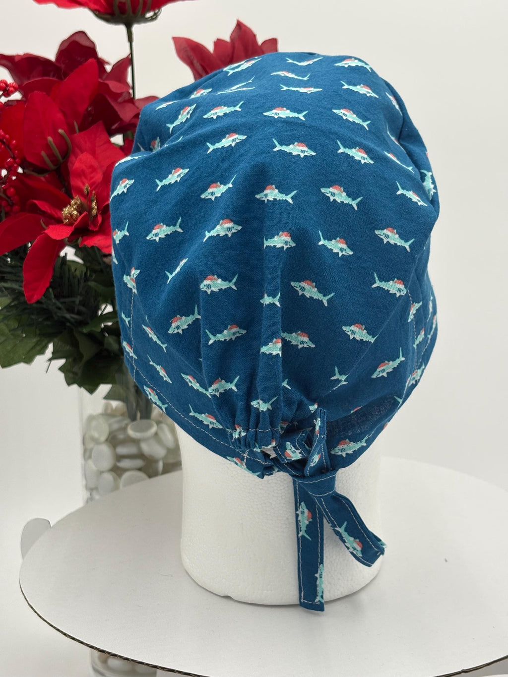 Blue scrub cap with shark pattern on a mannequin head against a white background