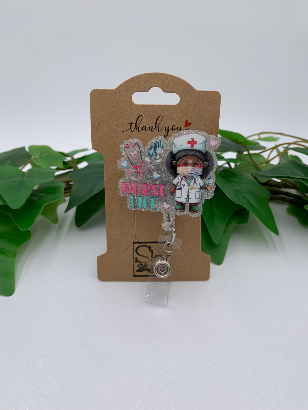 Badge holder with nurse design on a cardboard backing, surrounded by green leaves.