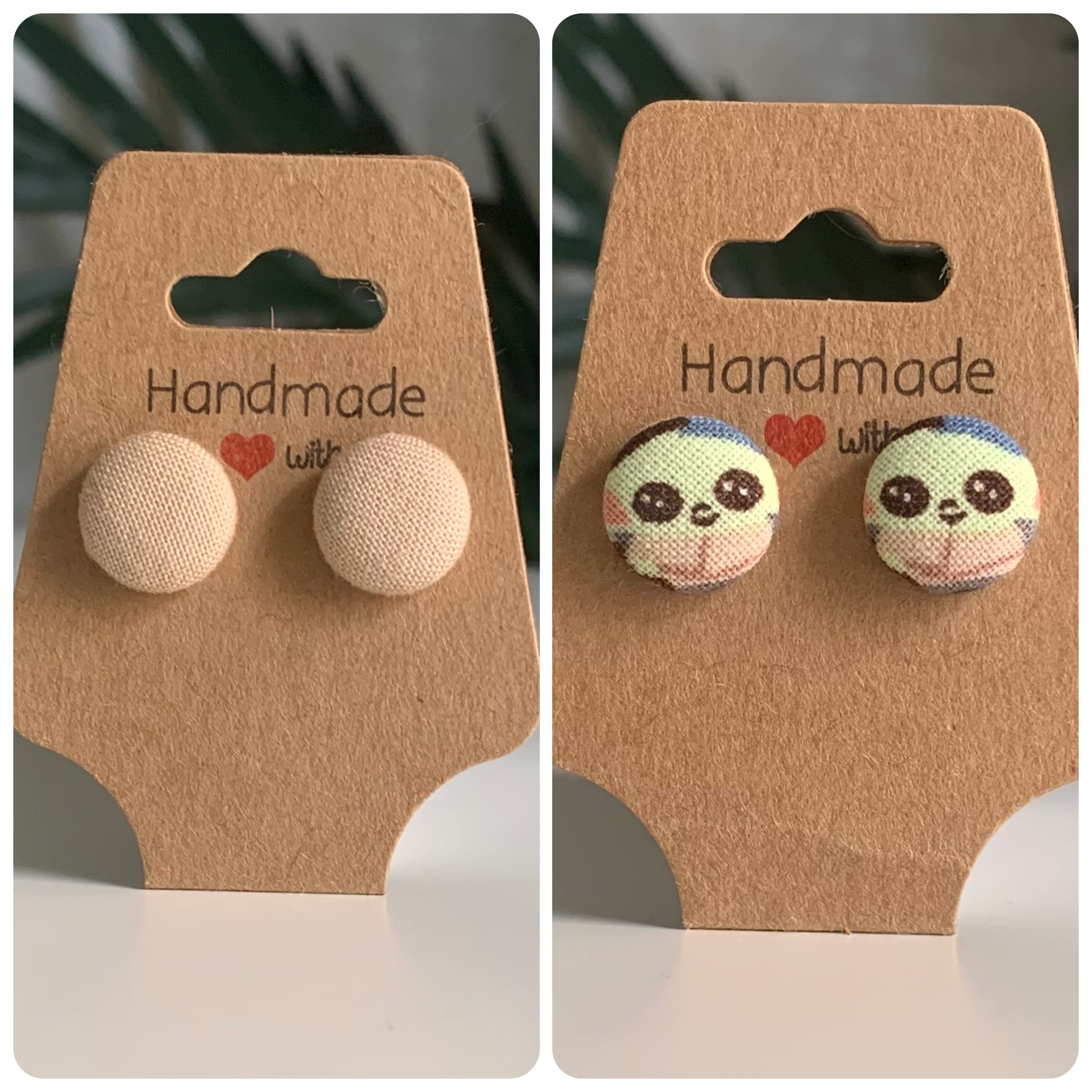 Two pairs of earrings one tan and the other is baby yoda on 'Handmade with Love' cards against a dark background.