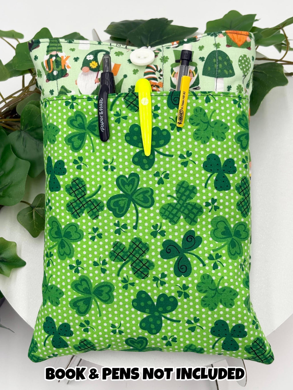 Green saint Patrick’s day gnomes and shamrocks patterned book sleeve with pens and book on a white surface and text “book and pens not included”