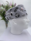 Gray scrub cap with black graphics on a mannequin head against a white background with flowers in the background