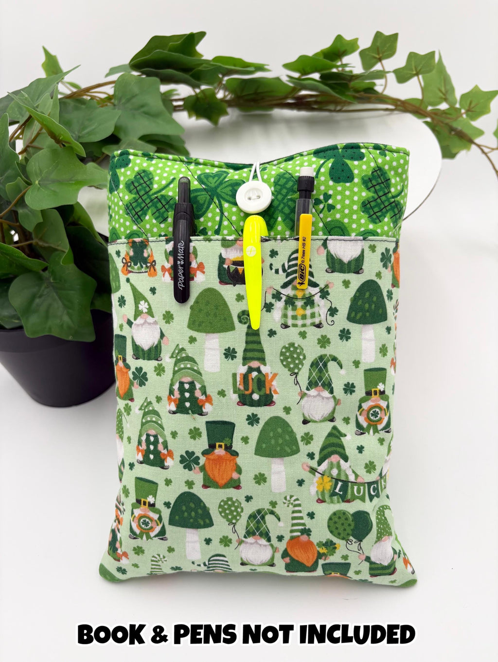 Green saint Patrick’s day gnomes and clovers patterned book sleeve with pens and book on a white surface and text “book and pens not included”