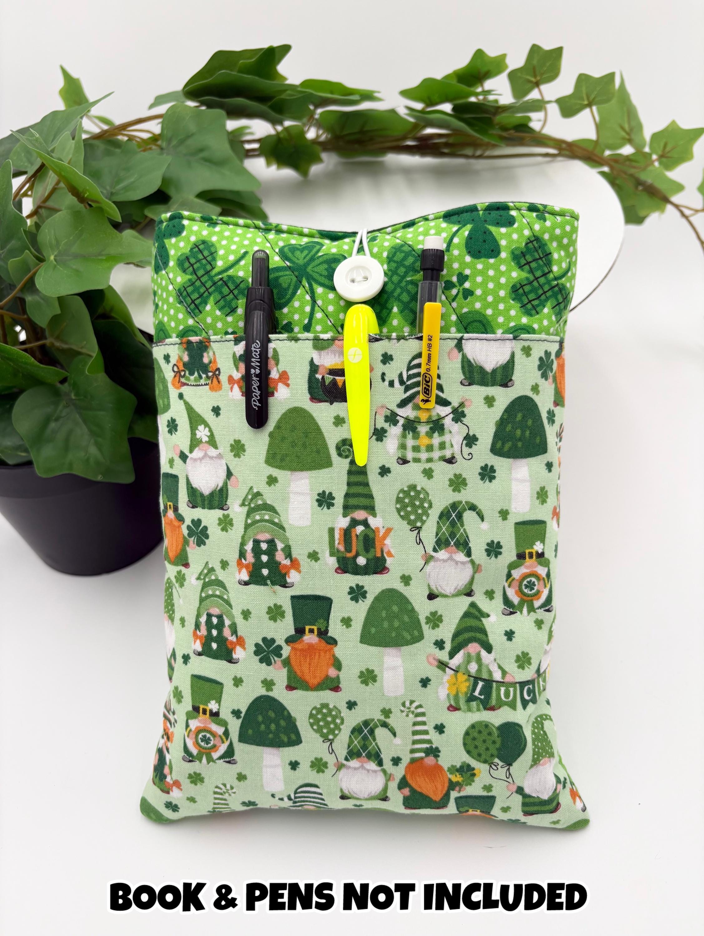 Green saint Patrick’s day gnomes and clovers patterned book sleeve with pens and book on a white surface and text “book and pens not included”