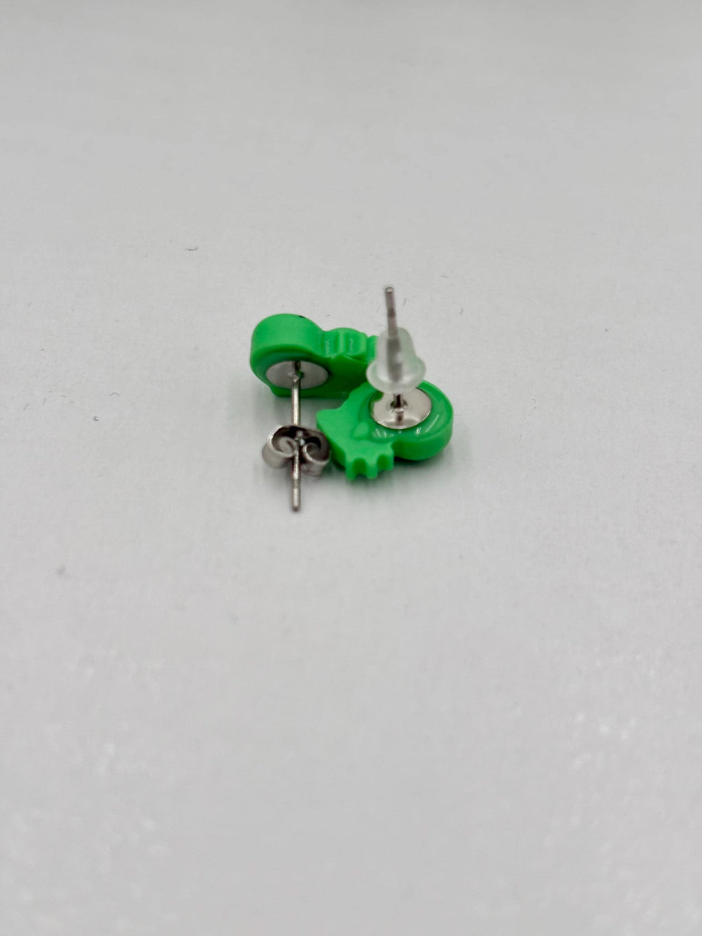 Green dinosaur shapped earrings  on a white background