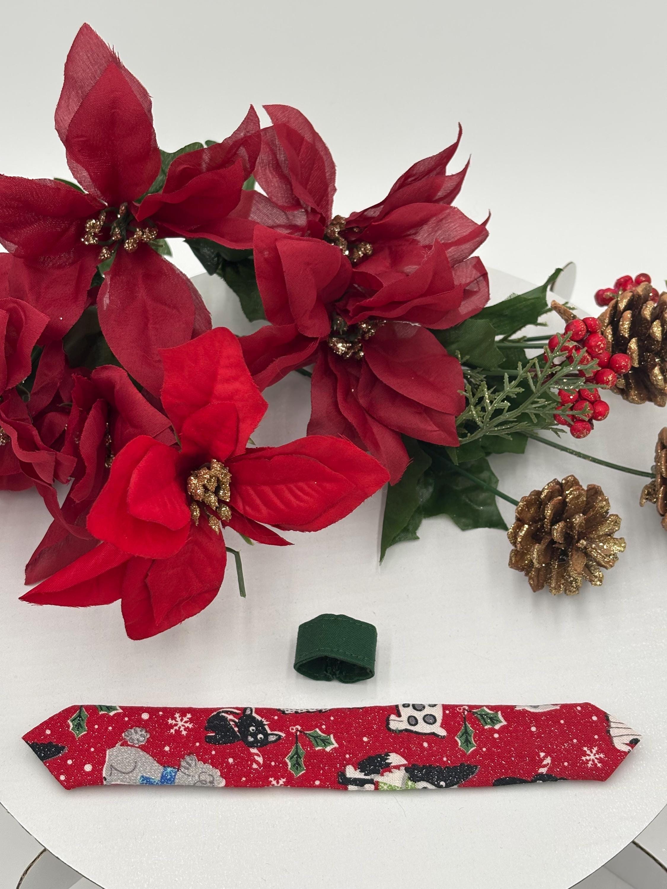 Red over the collar necktie with christmas dog design displayed fully opened with Red poinsettias with decorative ribbon on a white background