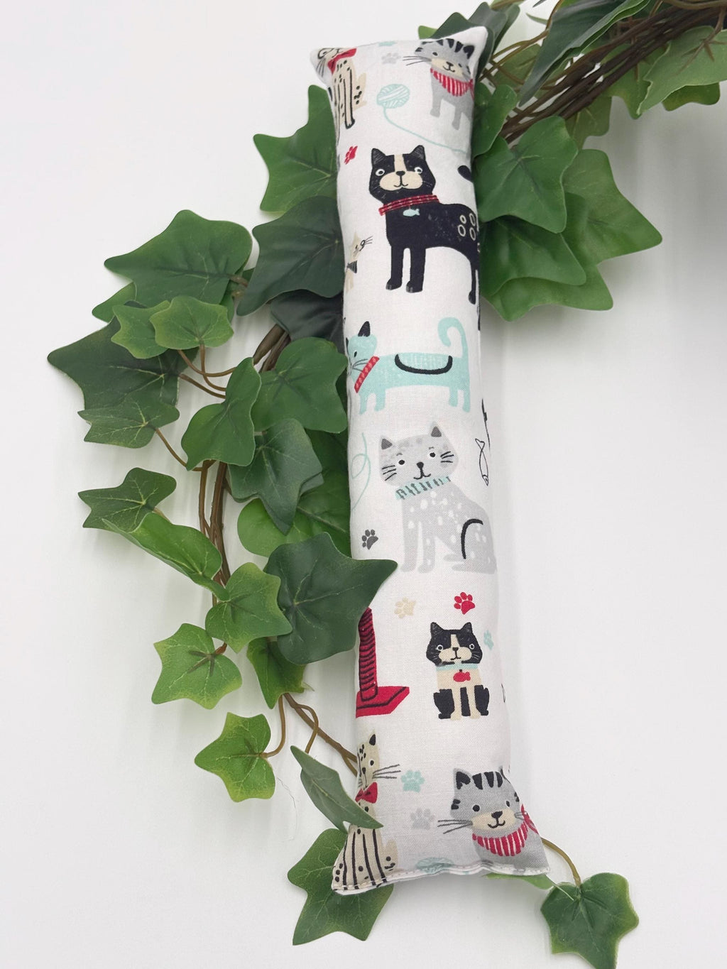One 2 inch wide cylindrical catnip toy with cat illustrations on a white background with green leaves.