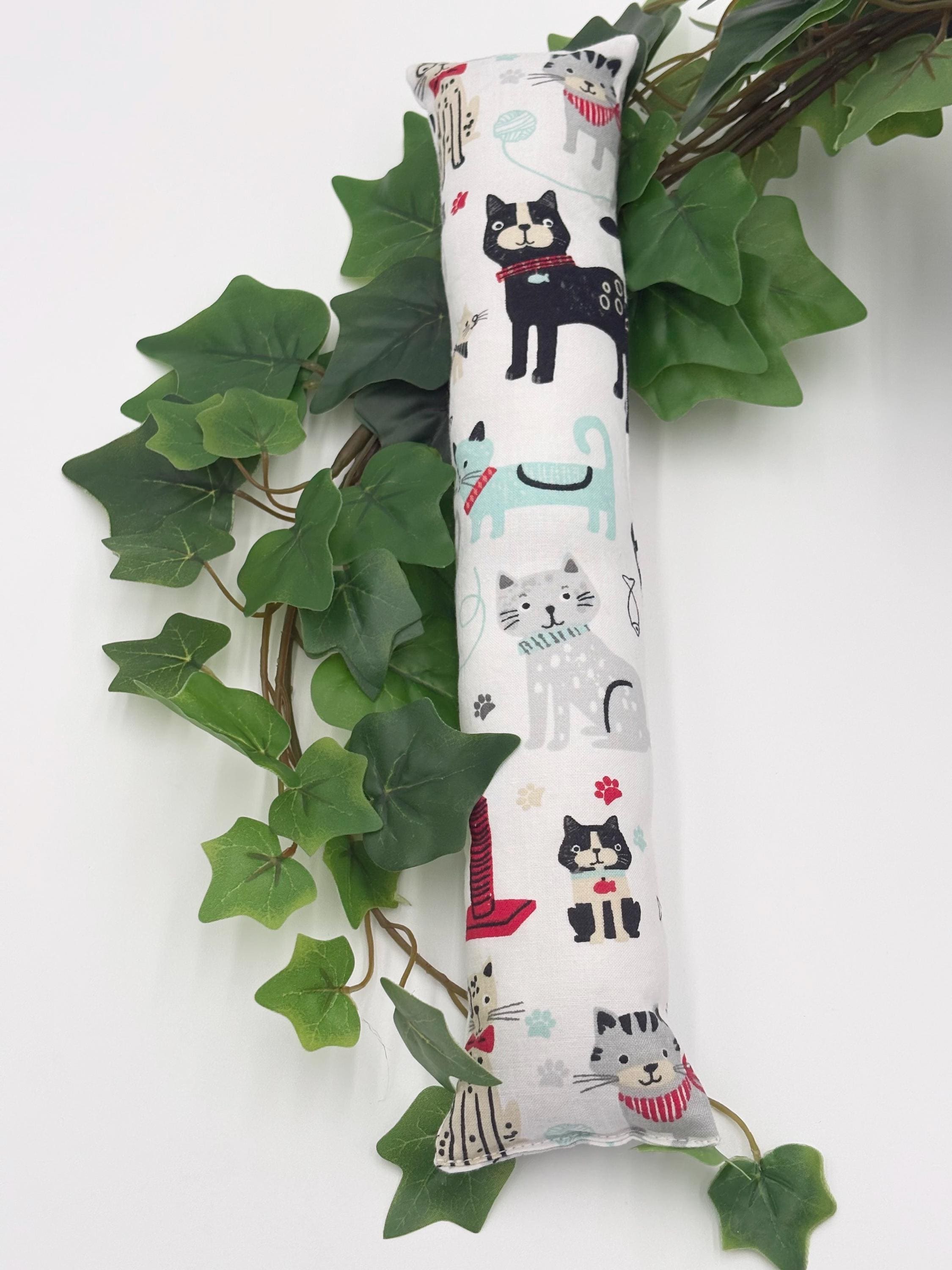 One 2 inch wide cylindrical catnip toy with cat illustrations on a white background with green leaves.