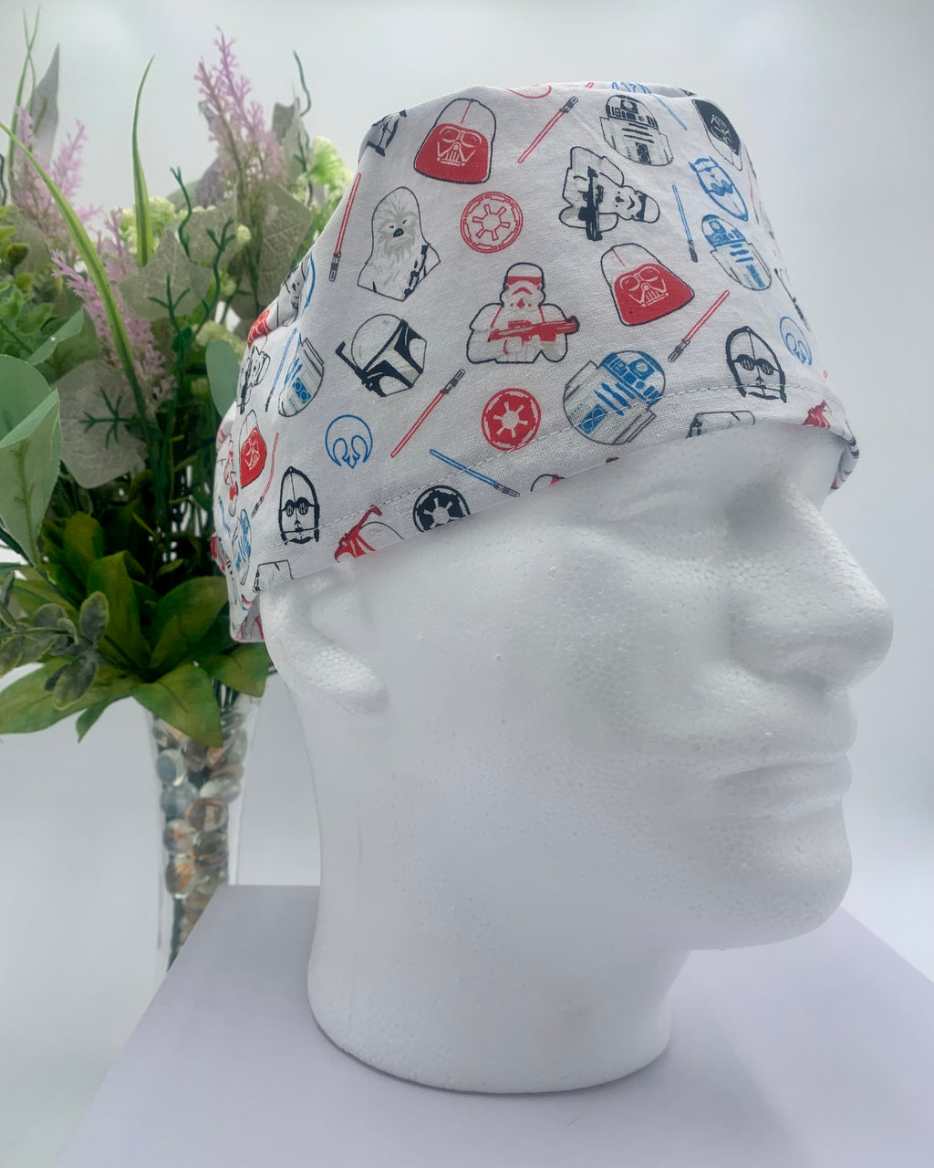 Star Wars white patterned scrub cap on a mannequin head with a white background with flowers