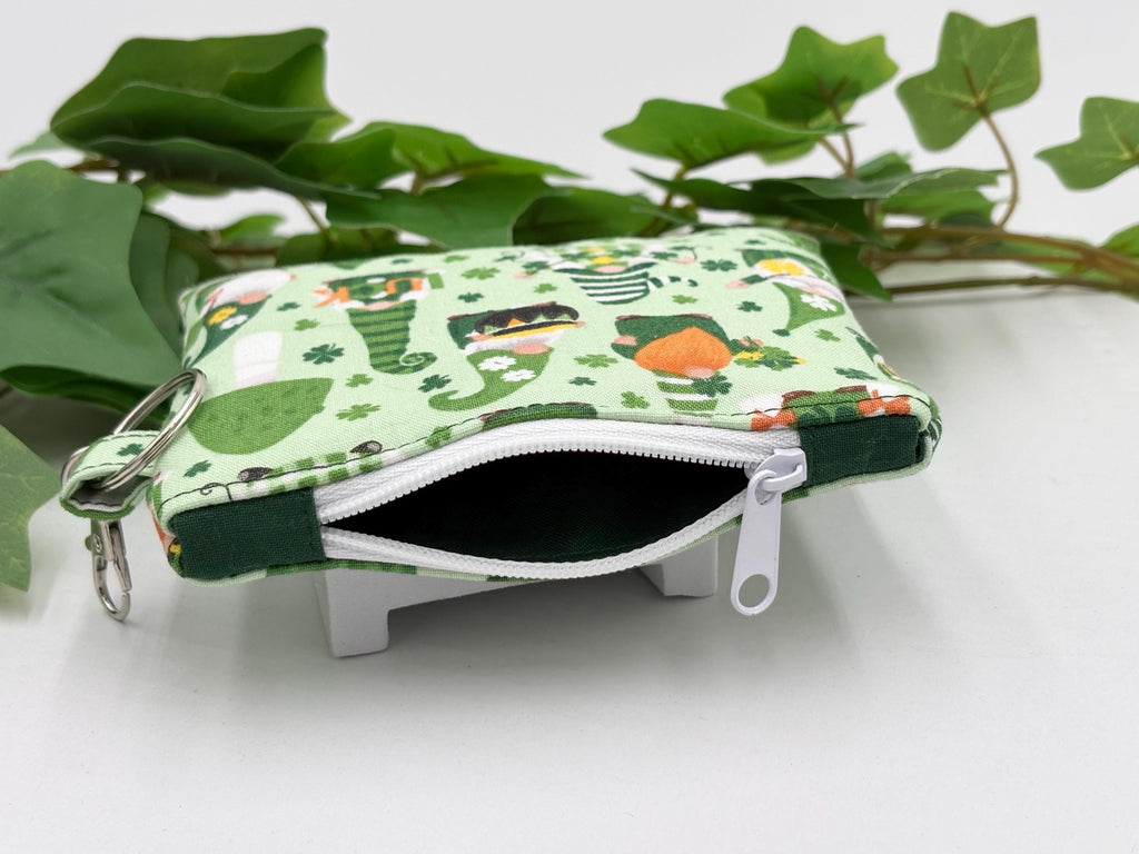 Small coin purse keychain with green st. patrick's day gnomes pattern with white zipper opened showing dark green lining on a white background with green leaves