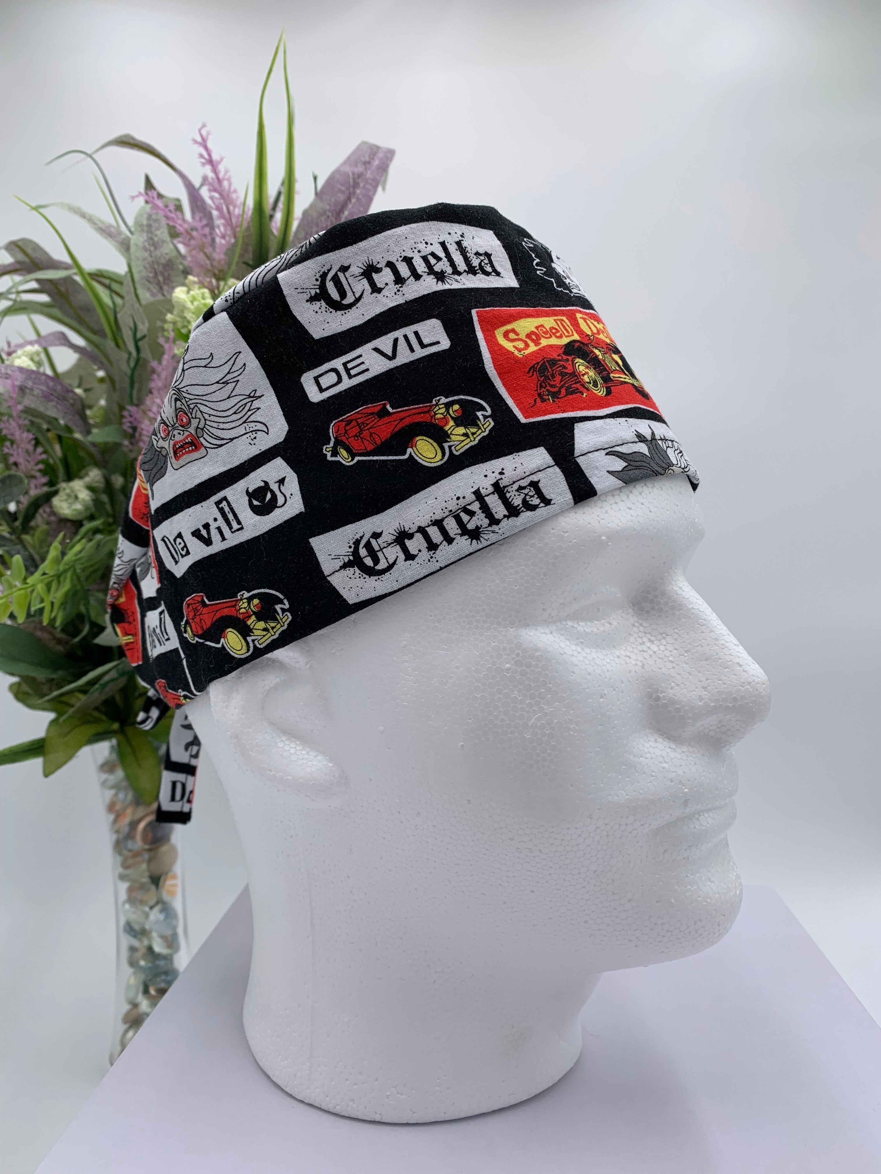 Mannequin head wearing a Cruella DeVil scrub cap with a decorative plant in the background.
