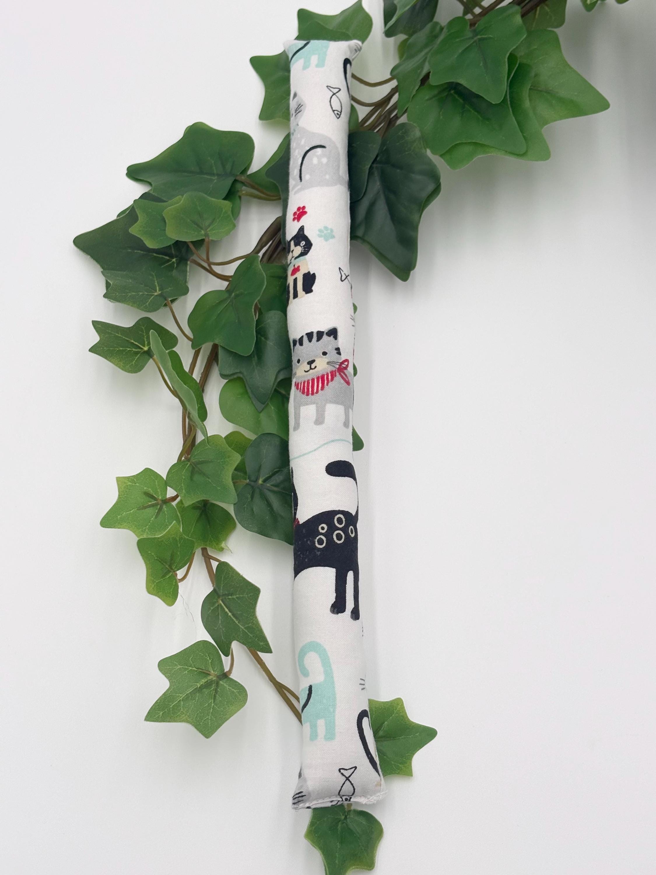 One 1 inch wide cylindrical catnip toy with cat illustrations on a white background with green leaves.