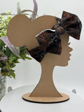 Black Headband with a decorative orange and white fireworks themed big bow on a mannequin head silhouette against a white background