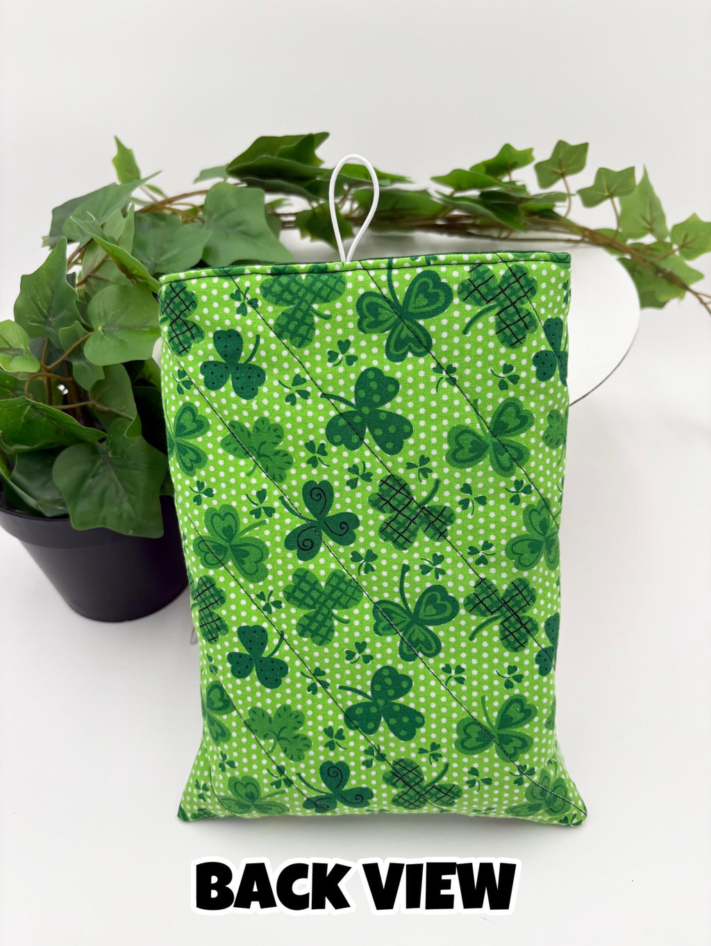 Green saint Patrick’s day clovers patterned book sleeve on a white surface and text “back view”