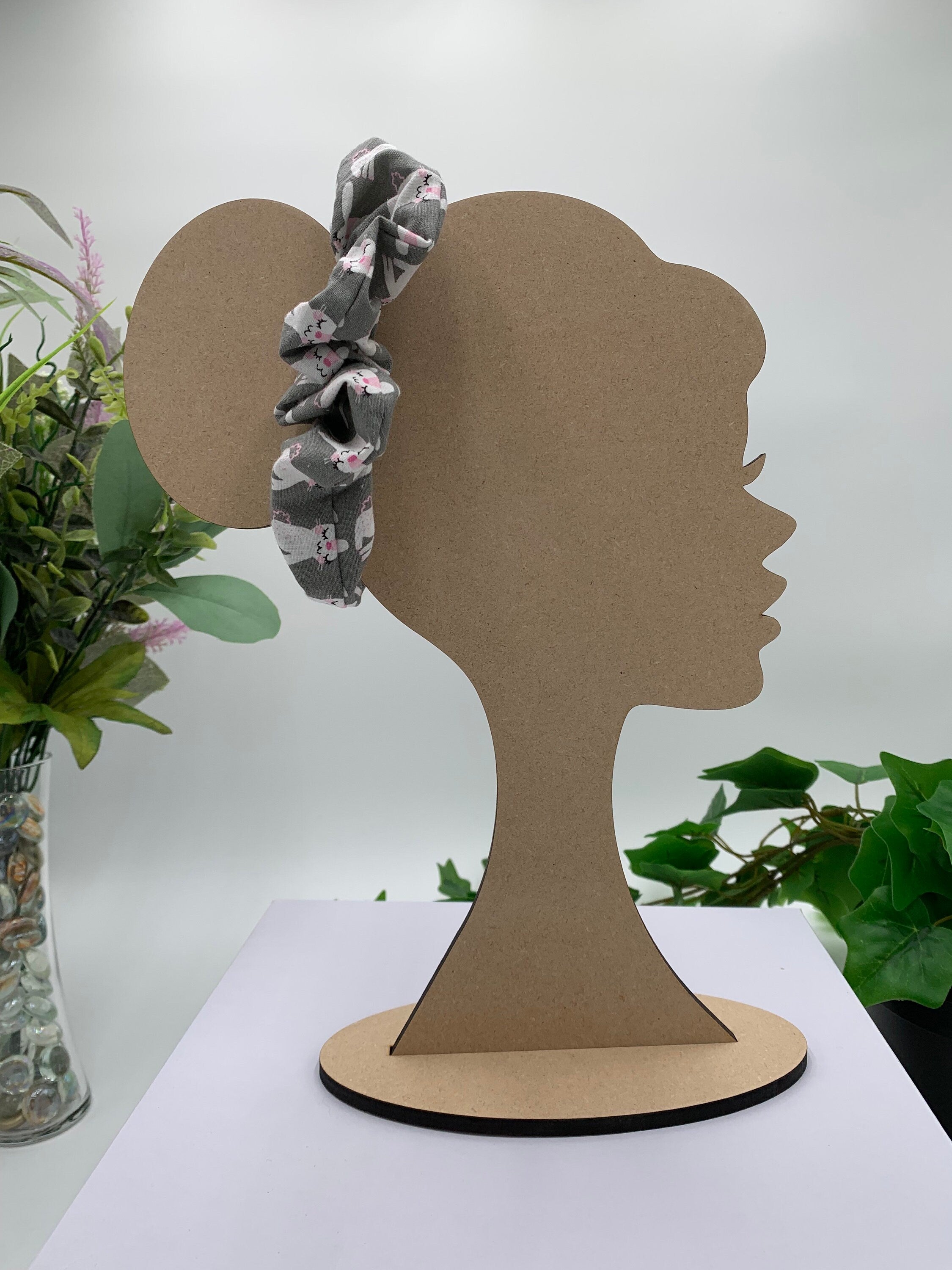 gray with with bunny print scrunchie on a cardboard silhouette of a head with plants in the background