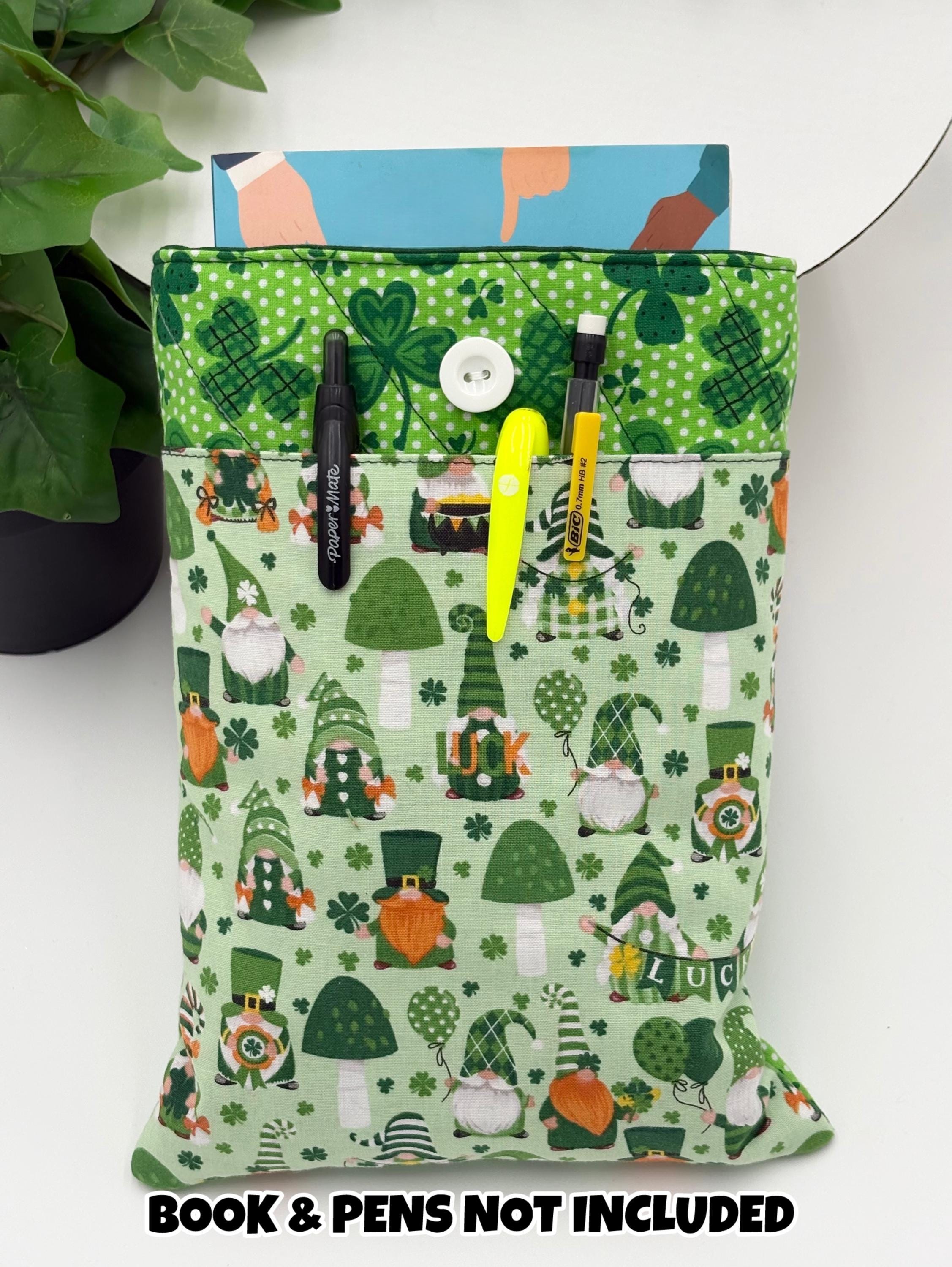 Green saint Patrick’s day gnomes and clovers patterned book sleeve with pens and book on a white surface and text “book and pens not included”
