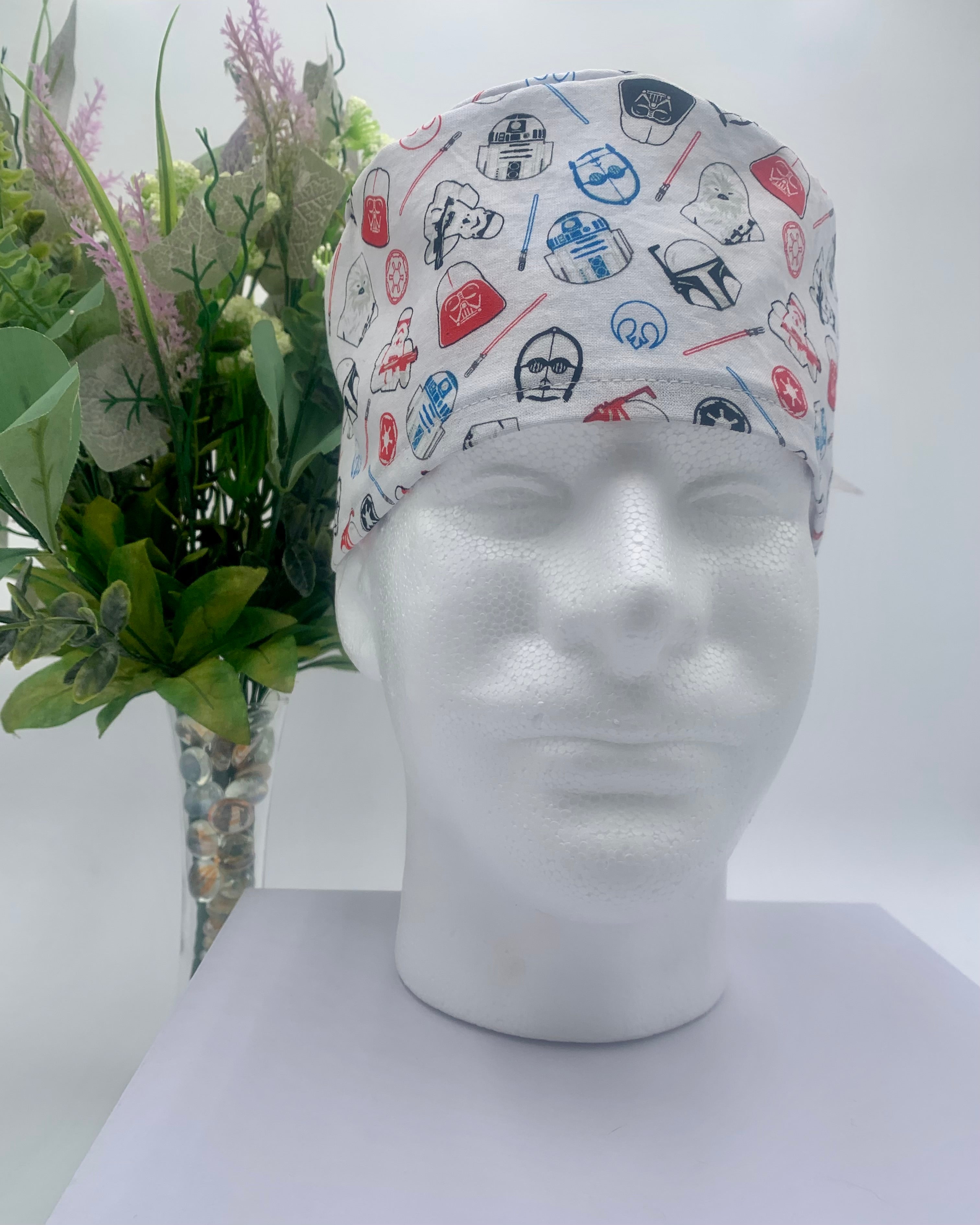 Star Wars white patterned scrub cap on a mannequin head with a white background with flowers