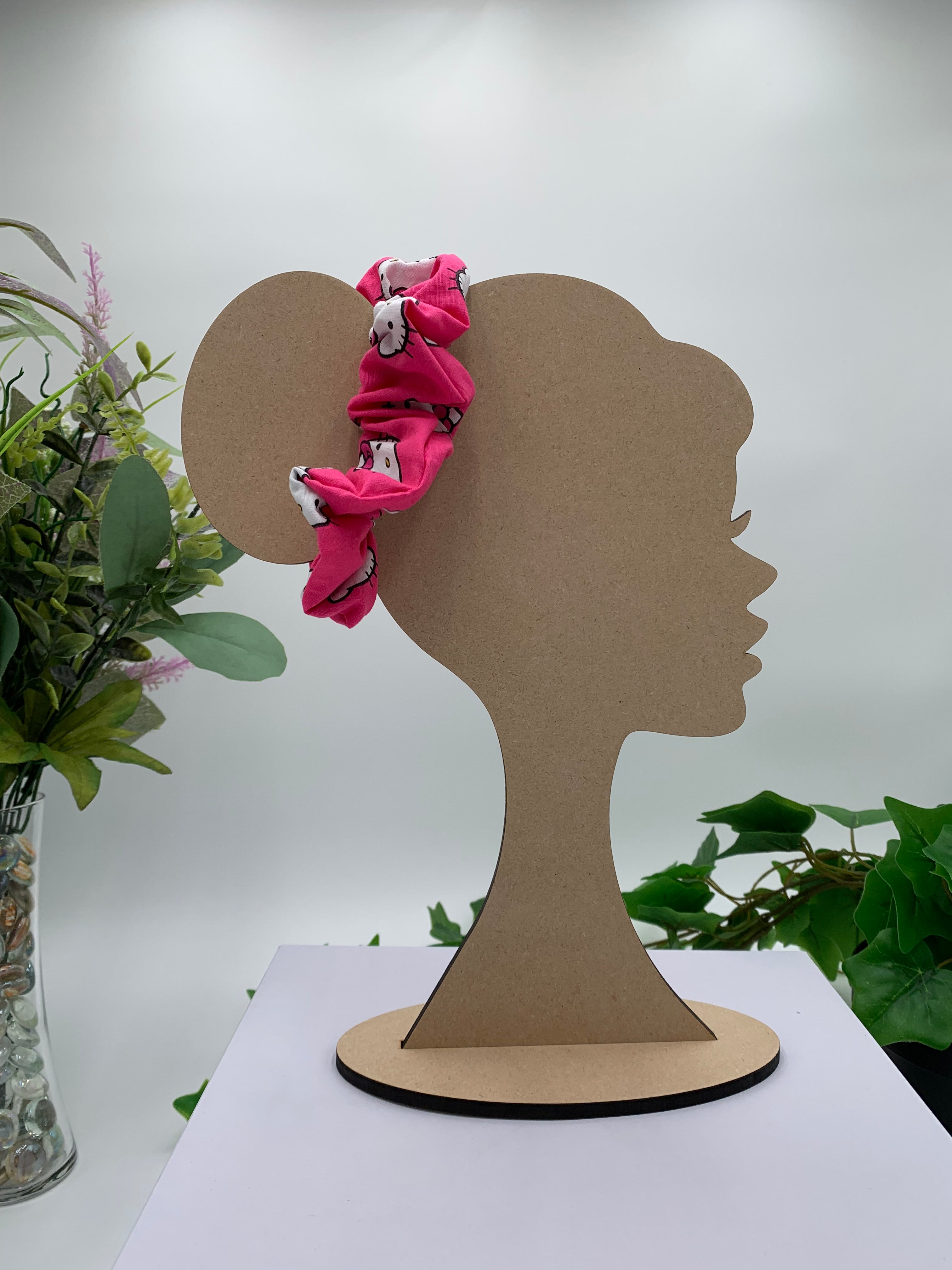 Mannequin Silhouette head with a cat themed scrunchie on a white background with greenery