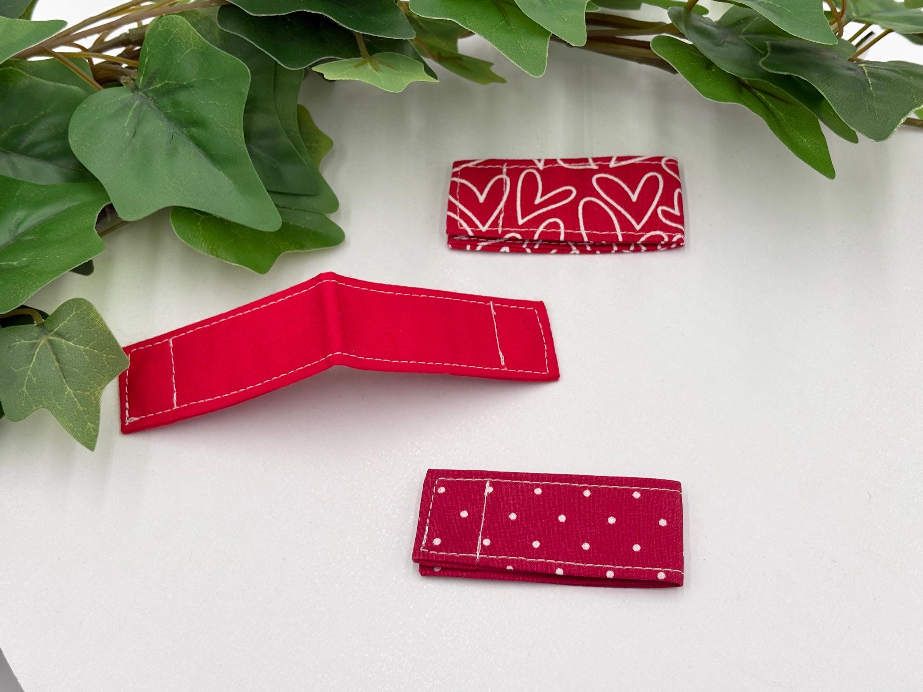 Three Red multi-pattern magnetic bookmarks on a white surface with ivy leaves.