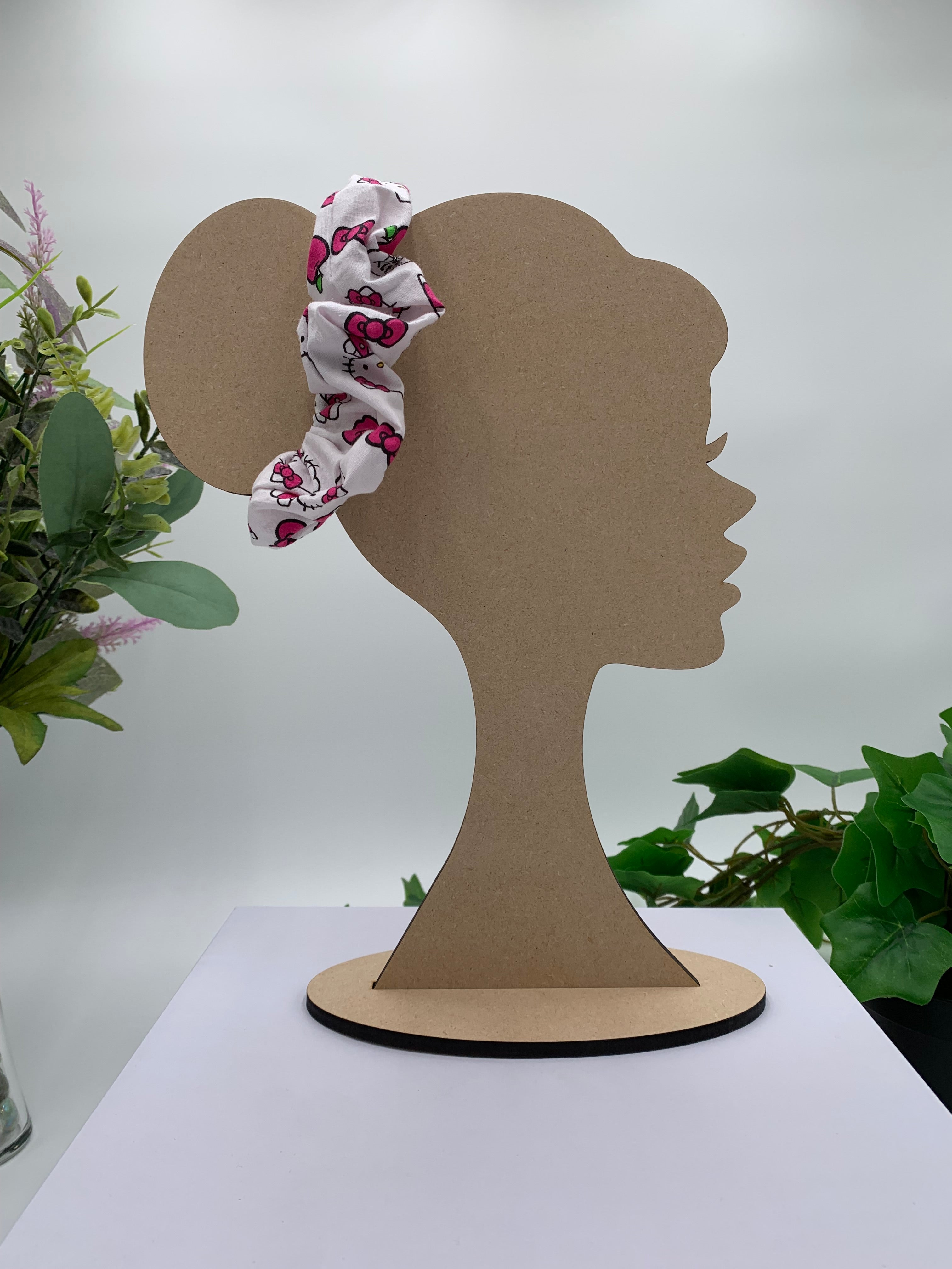 Mannequin Silhouette head with a cat themed scrunchie on a white background with greenery