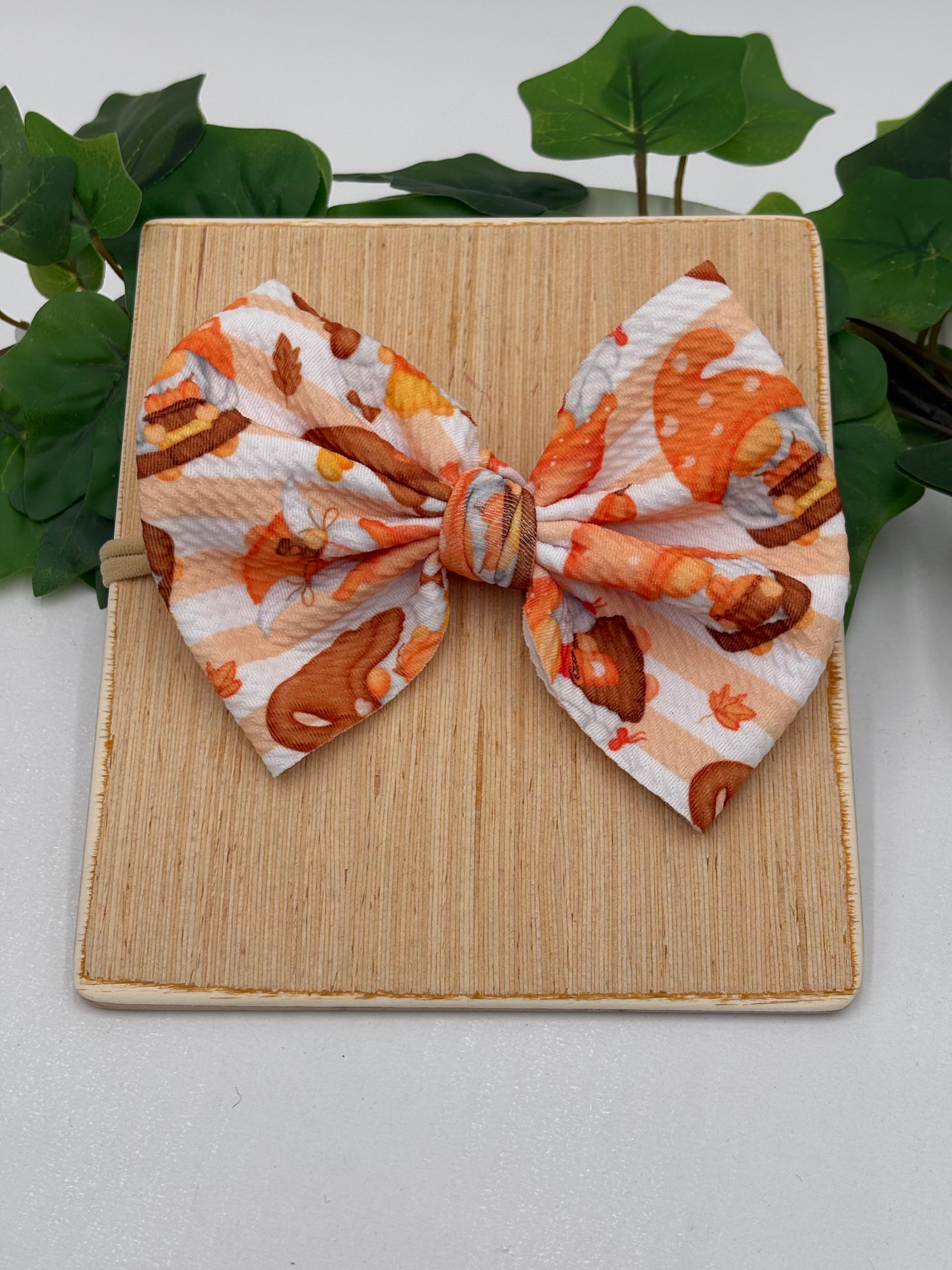 Autumn gnomes themed big bow nylon headband on a wooden board with a white background and greenery 