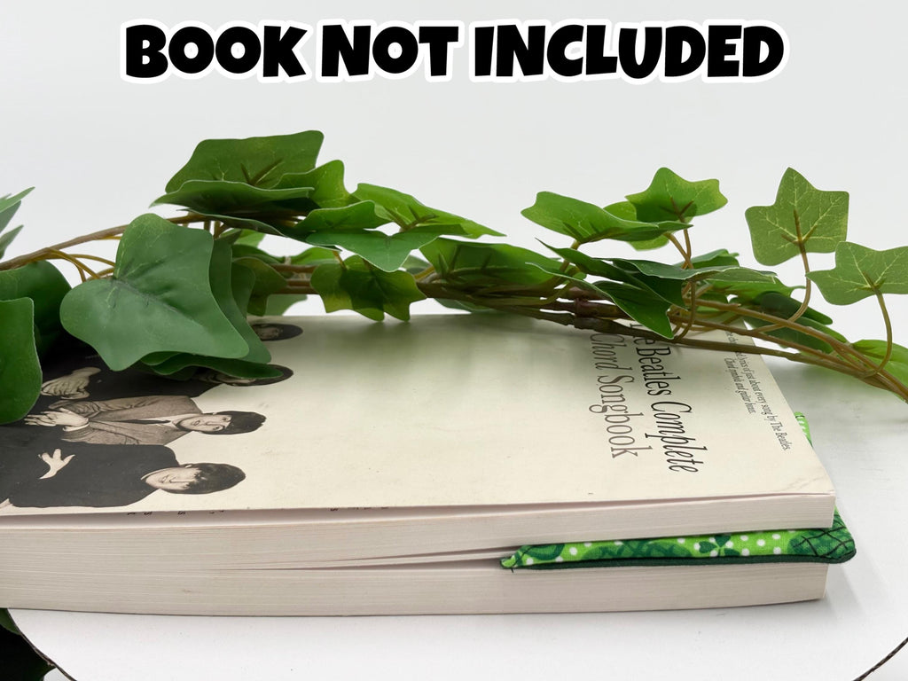Book with green corner bookmark attached with green leaves on a white surface, text 'Book Not Included' at the top.