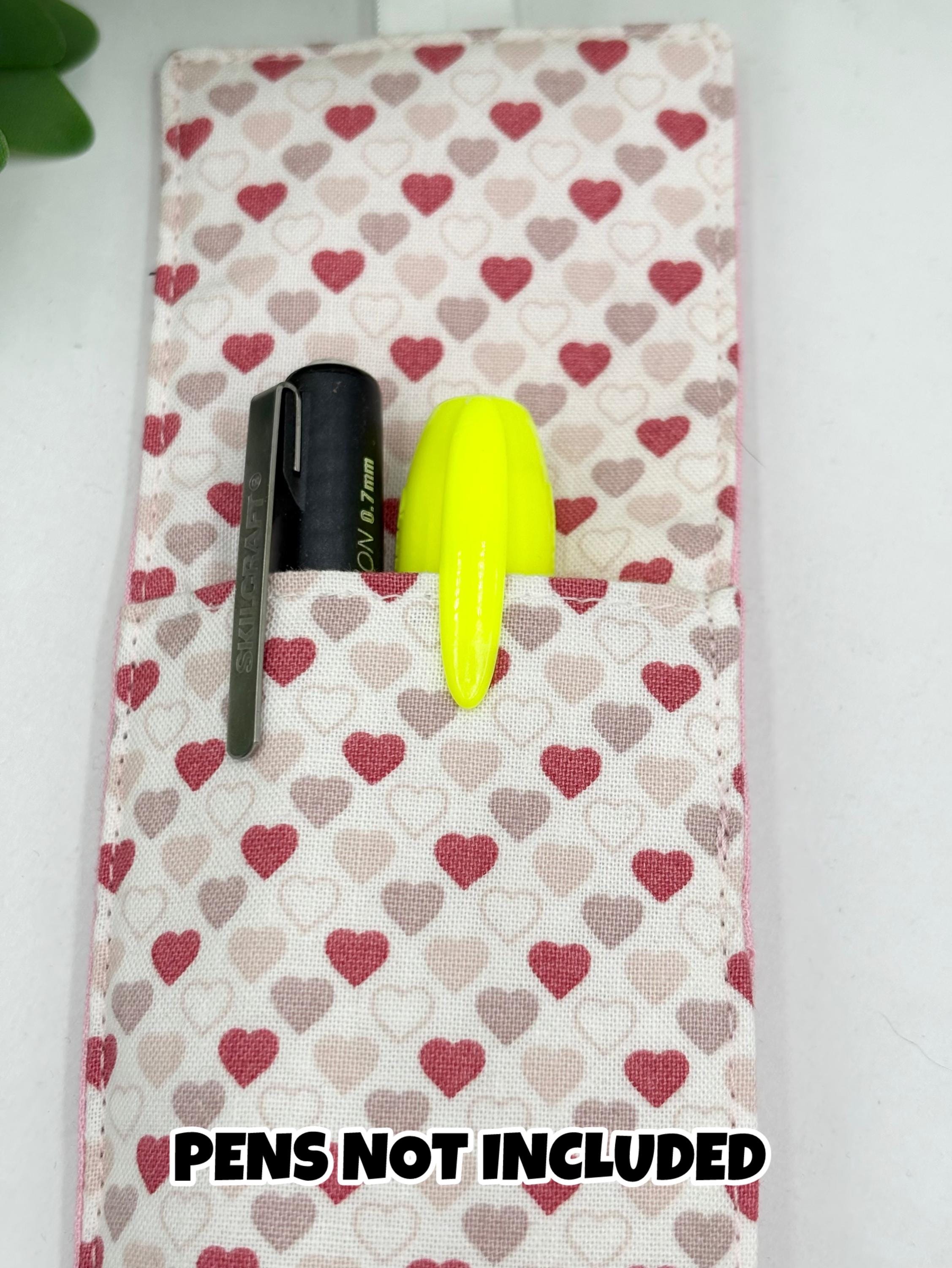 Heart-patterned fabric pen holder bookmark with a pen and yellow highlighter on top, on a white background.