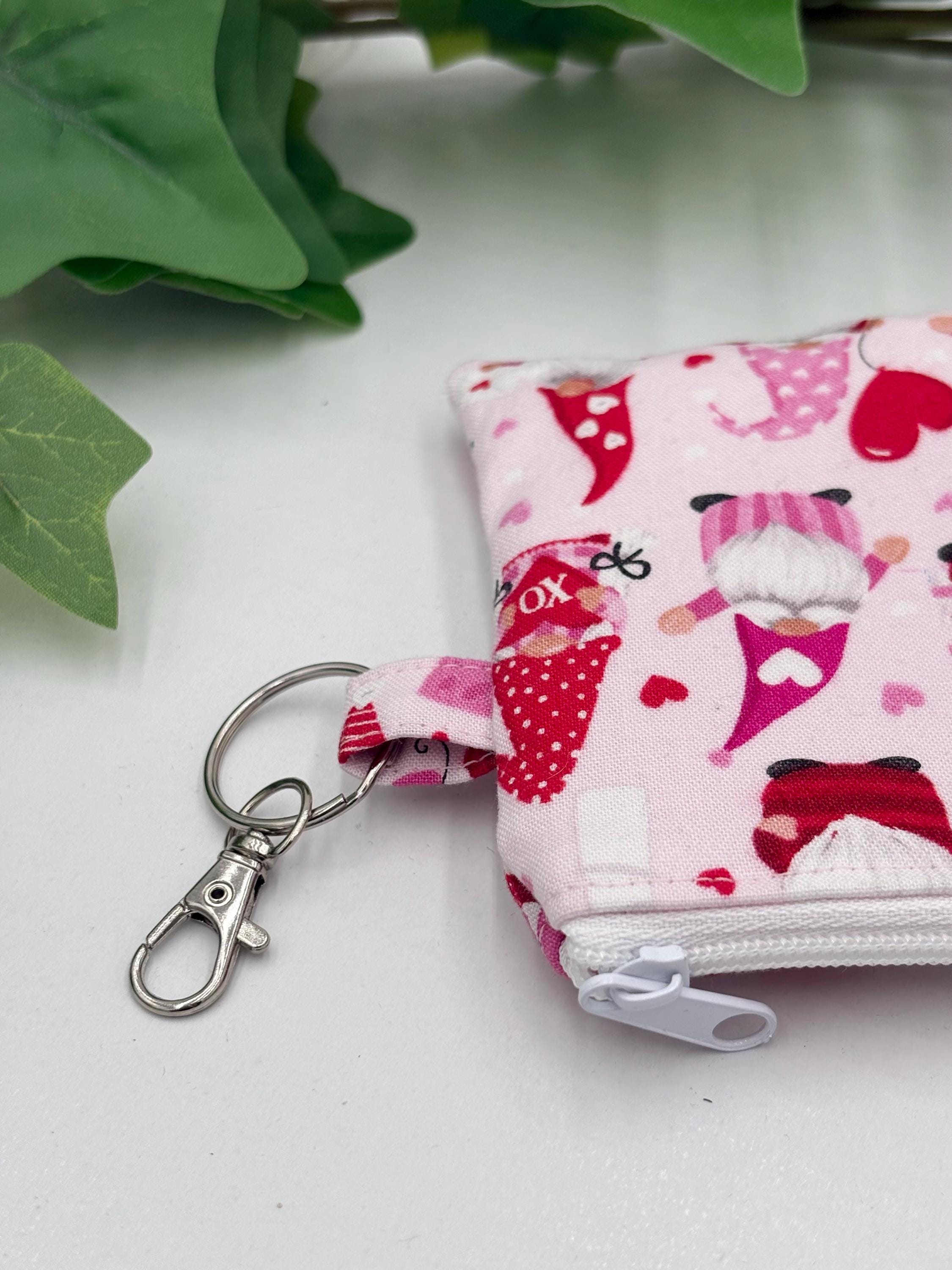 Close up of the keychain of the Small coin purse with Valentine-themed gnomes and hearts pattern on a white background with green leaves