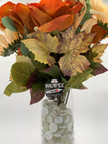 Bouquet of autumn-themed flowers with a 'Nurse in Progress' badge reel in a clear vase on a white background