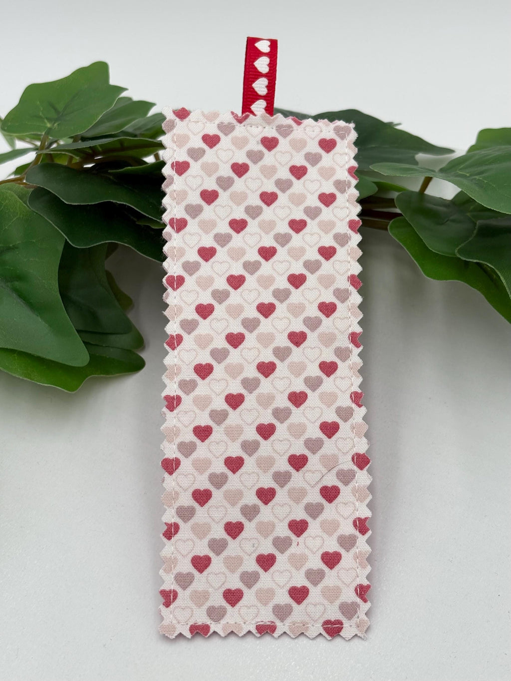 Fabric bookmark with heart pattern on a green leafy branch against a white background