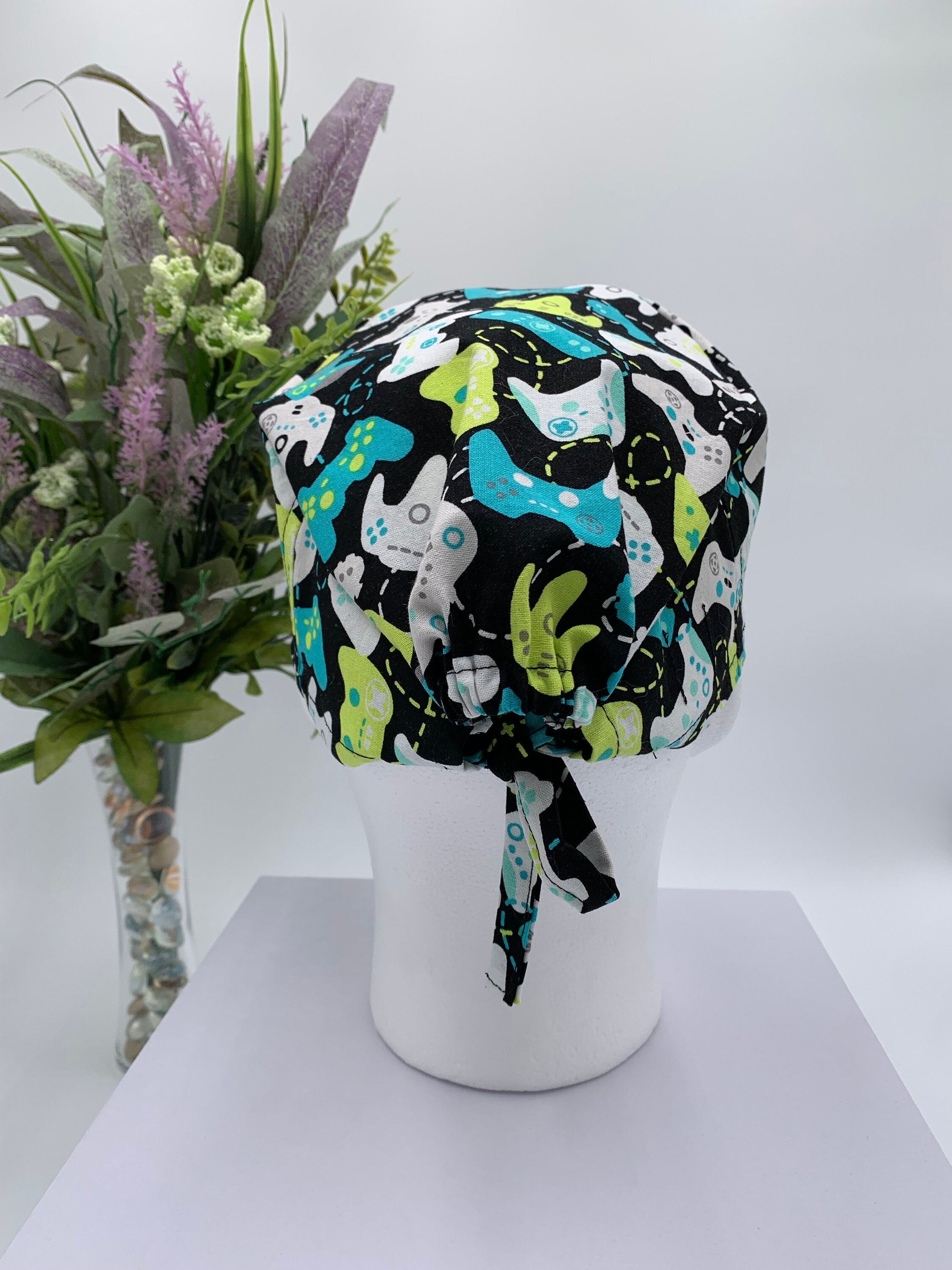 Colorful game controller scrub cap on a mannequin head with a bouquet of flowers in the background