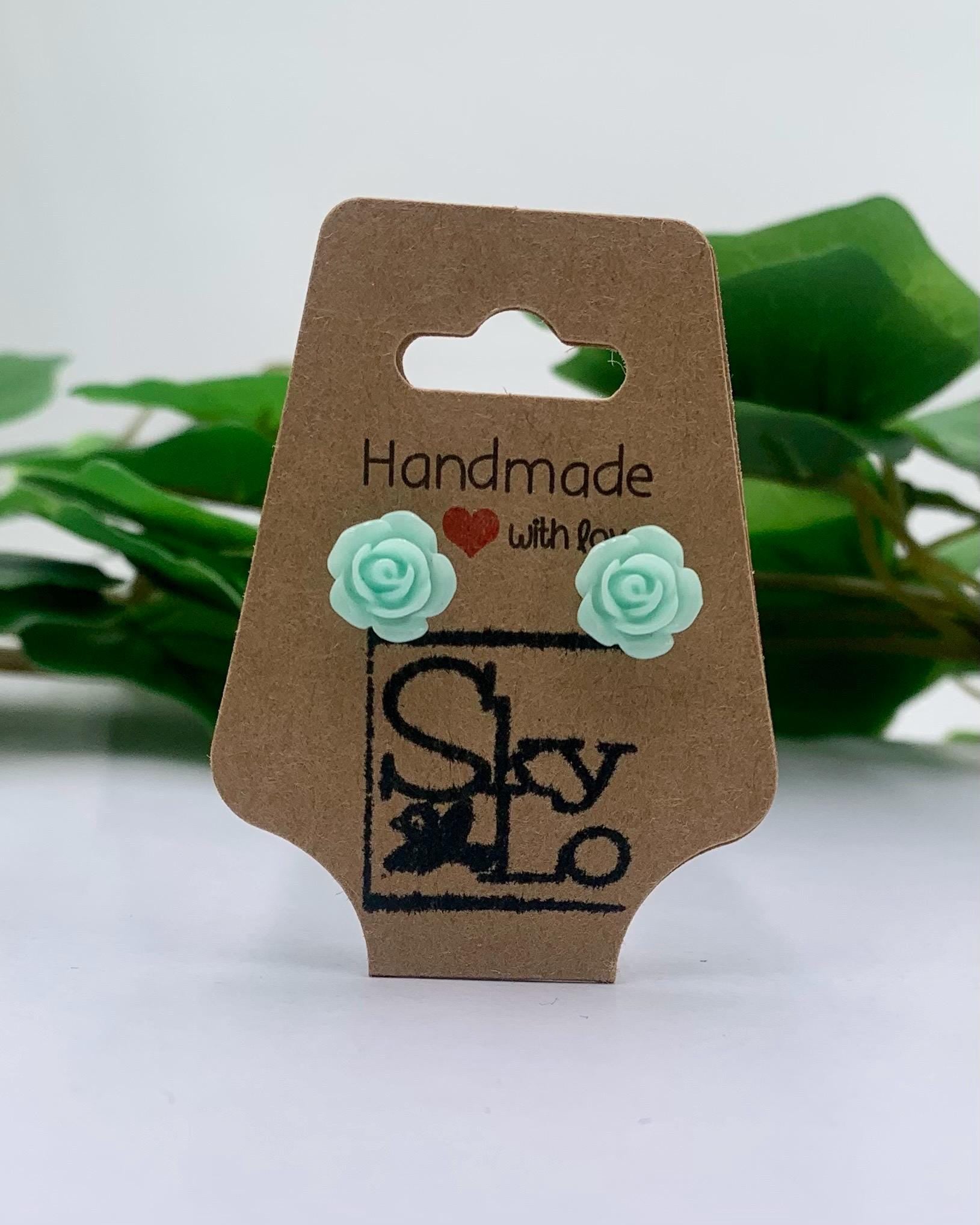 Pair of mint rose-shaped earrings on a 'Handmade with Love' branded card with a green leafy background.
