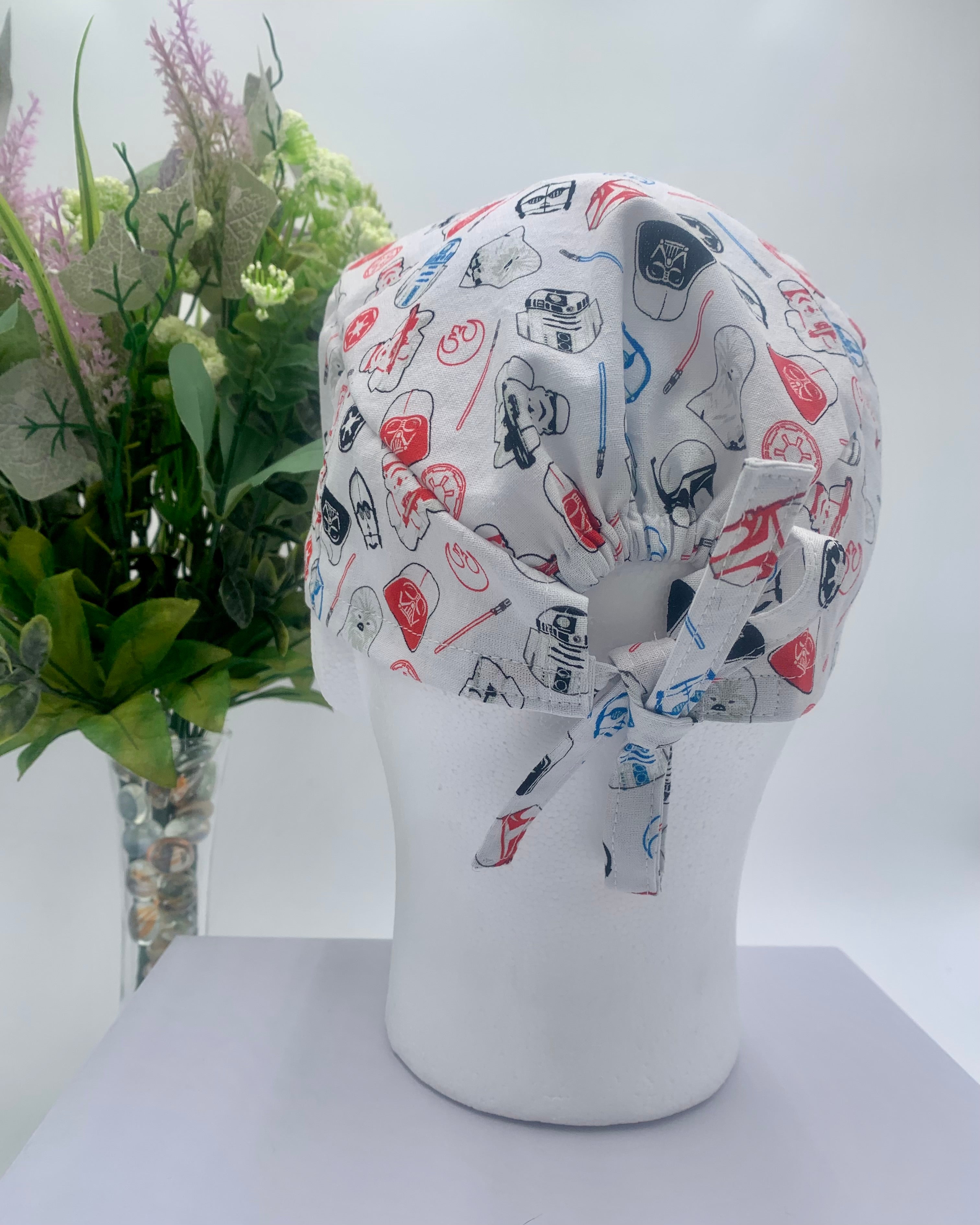 Star Wars white patterned scrub cap on a mannequin head with a white background with flowers