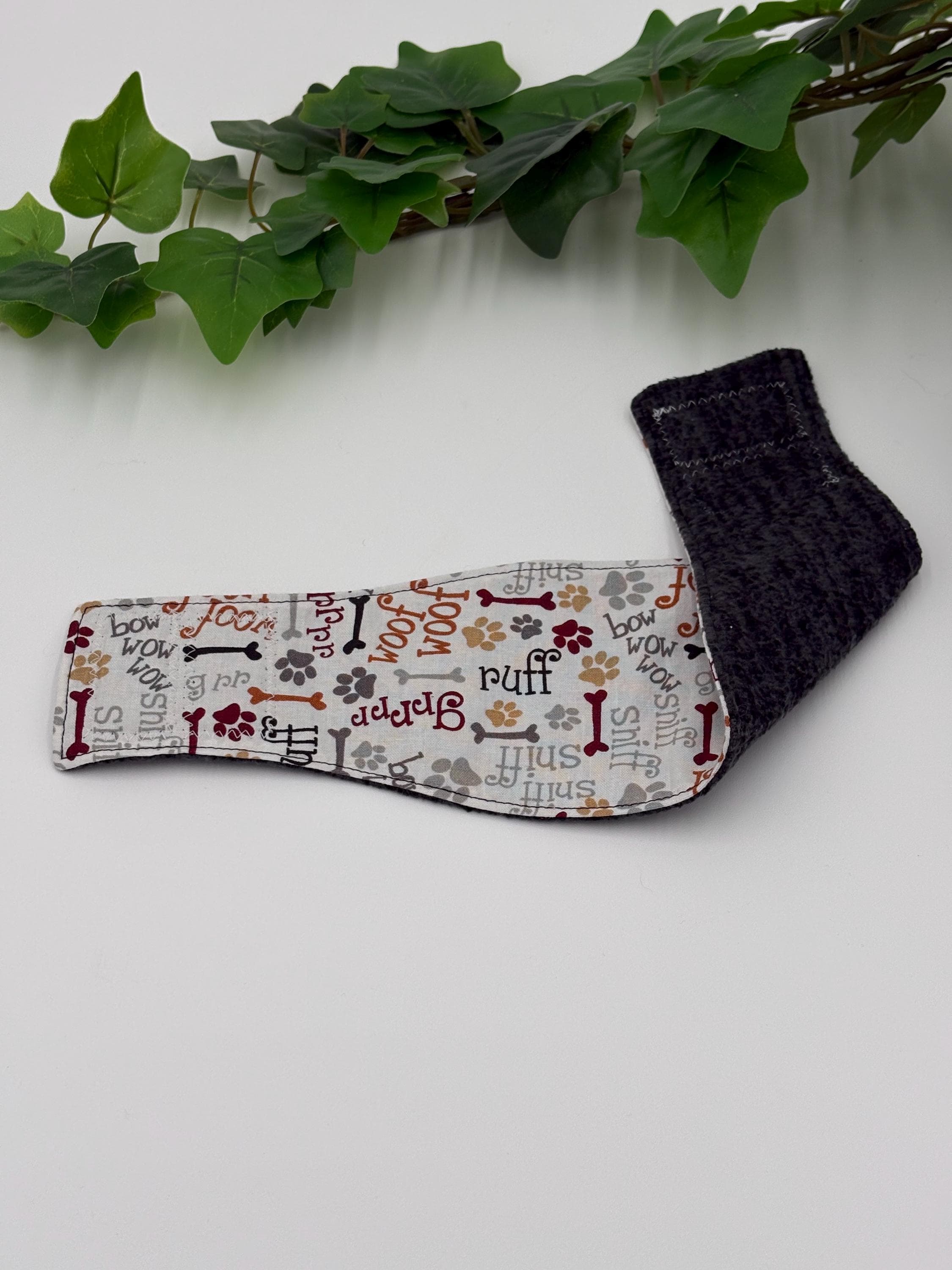 patterned belly band fully extended with inside folded over on a white background next to green plant