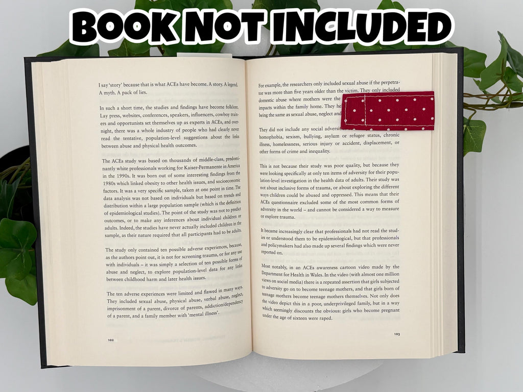 Open book with text and a red and white polka dot magnetic bookmark on a white background with text that says "Book Not Included"