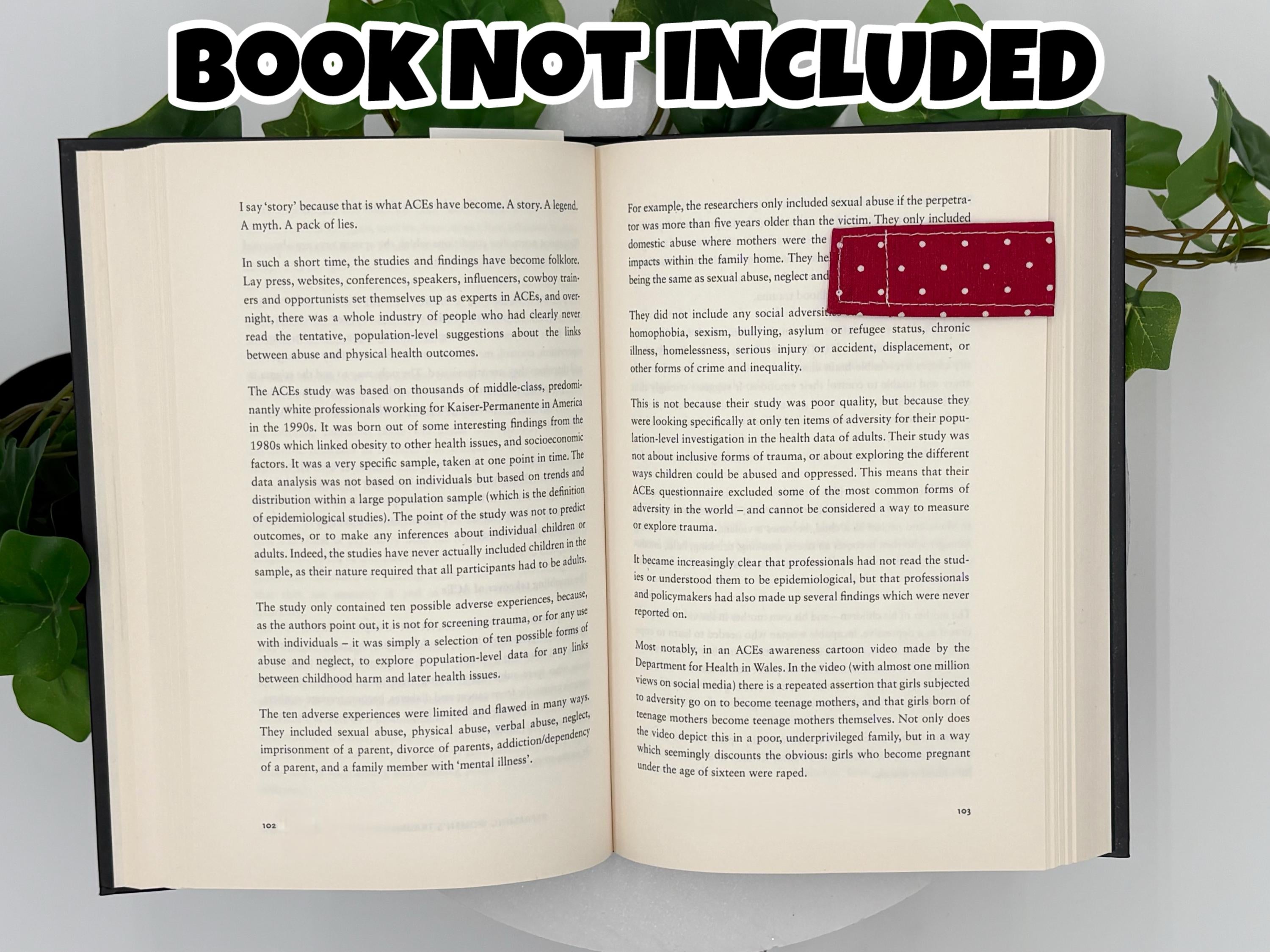 Open book with text and a red and white polka dot magnetic bookmark on a white background with text that says "Book Not Included"