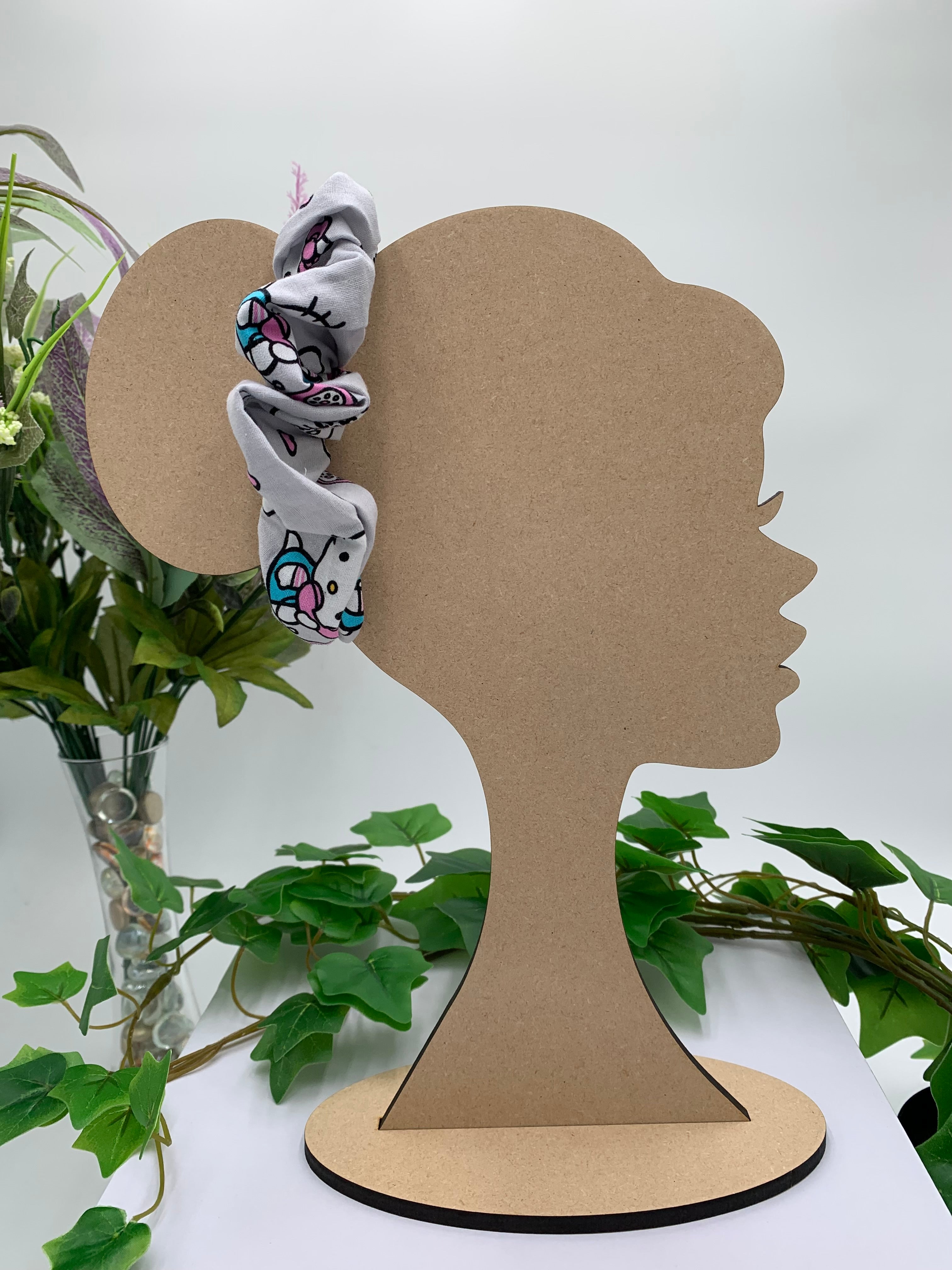 Mannequin Silhouette head with a cat themed scrunchie on a white background with greenery
