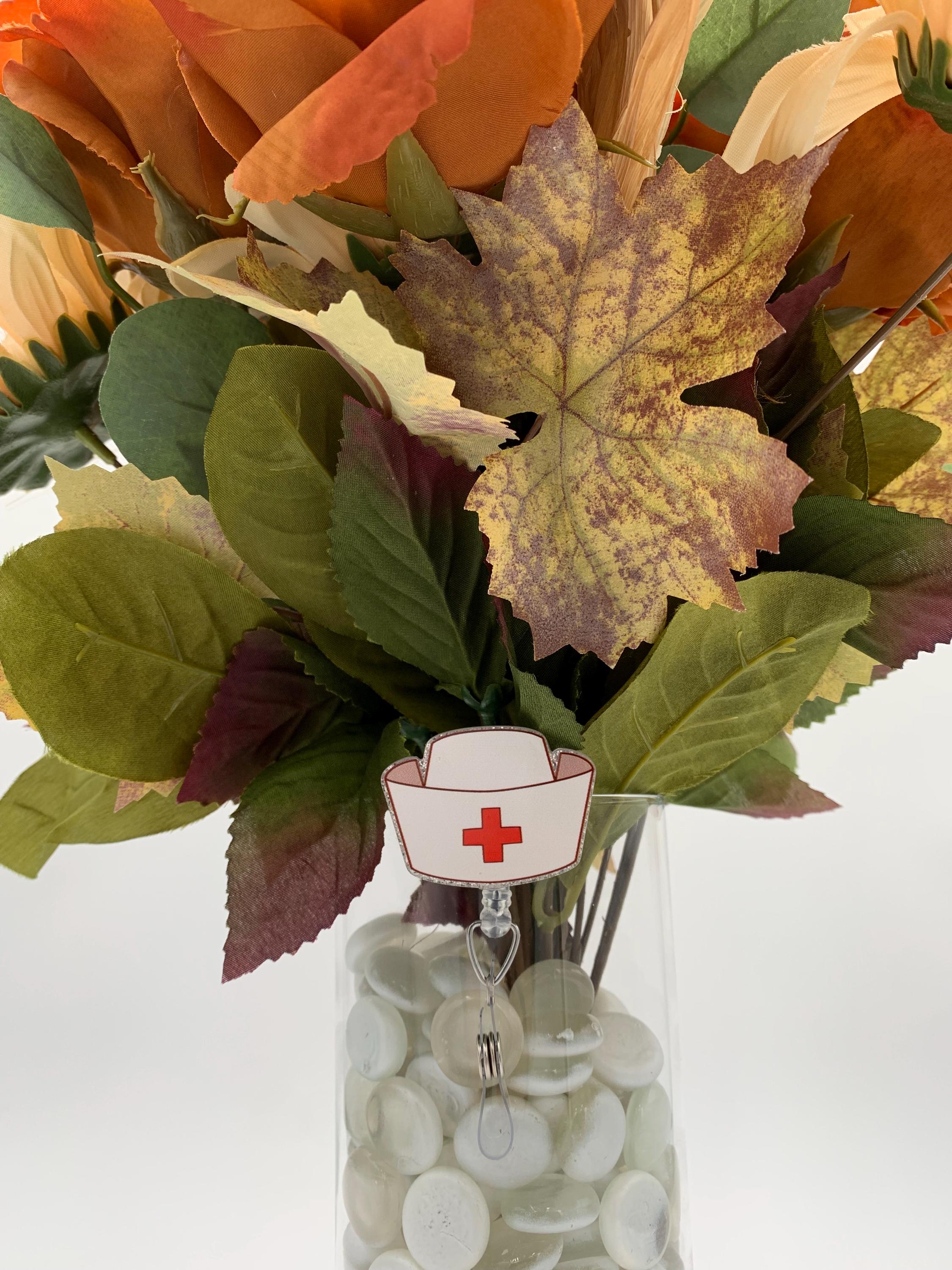 Bouquet of autumn leaves with a nurse's hat badge reel on a vase on a white background