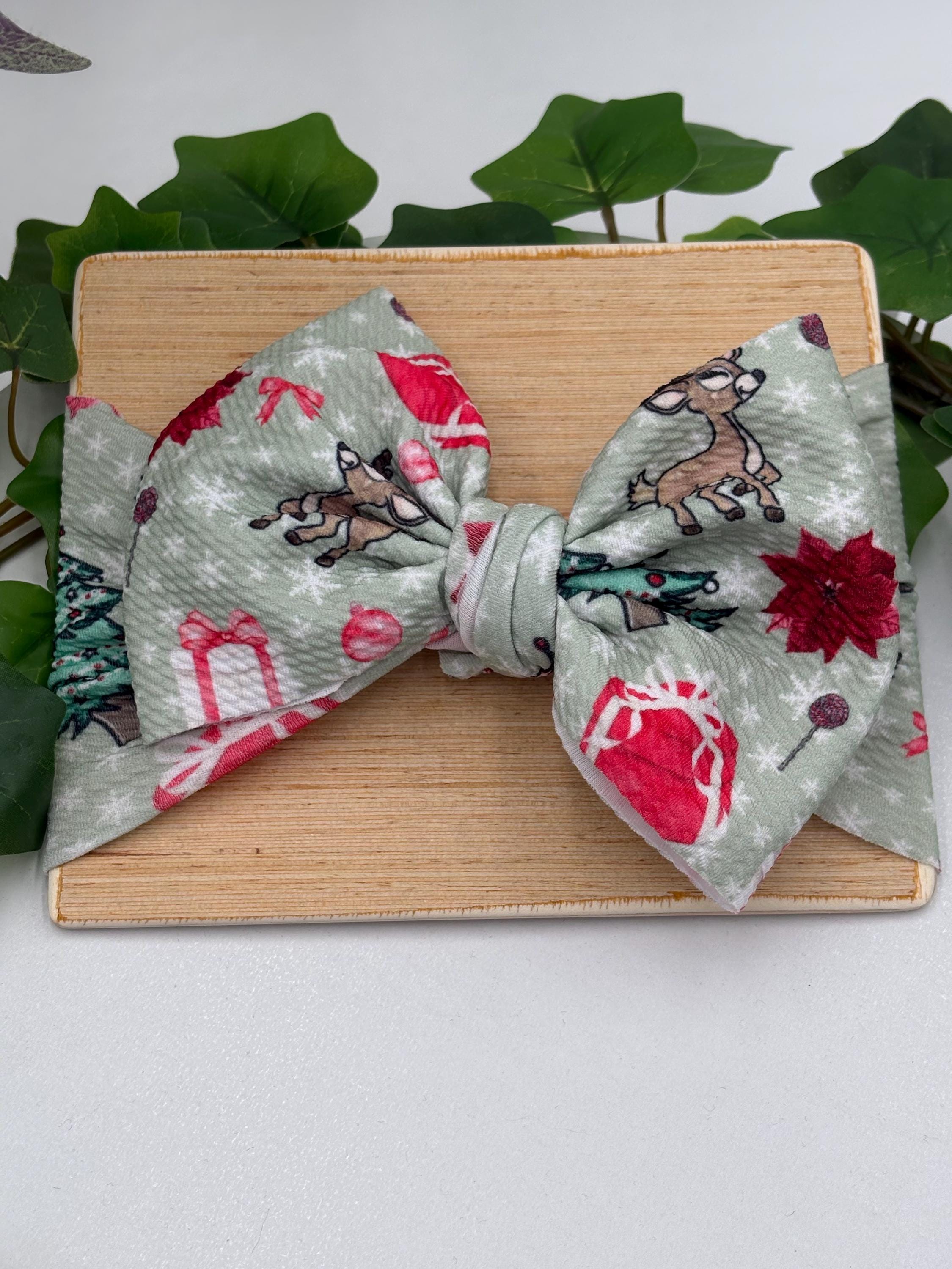 Headband with a decorative christmas themed big bow headband on a wooden plank against a white background