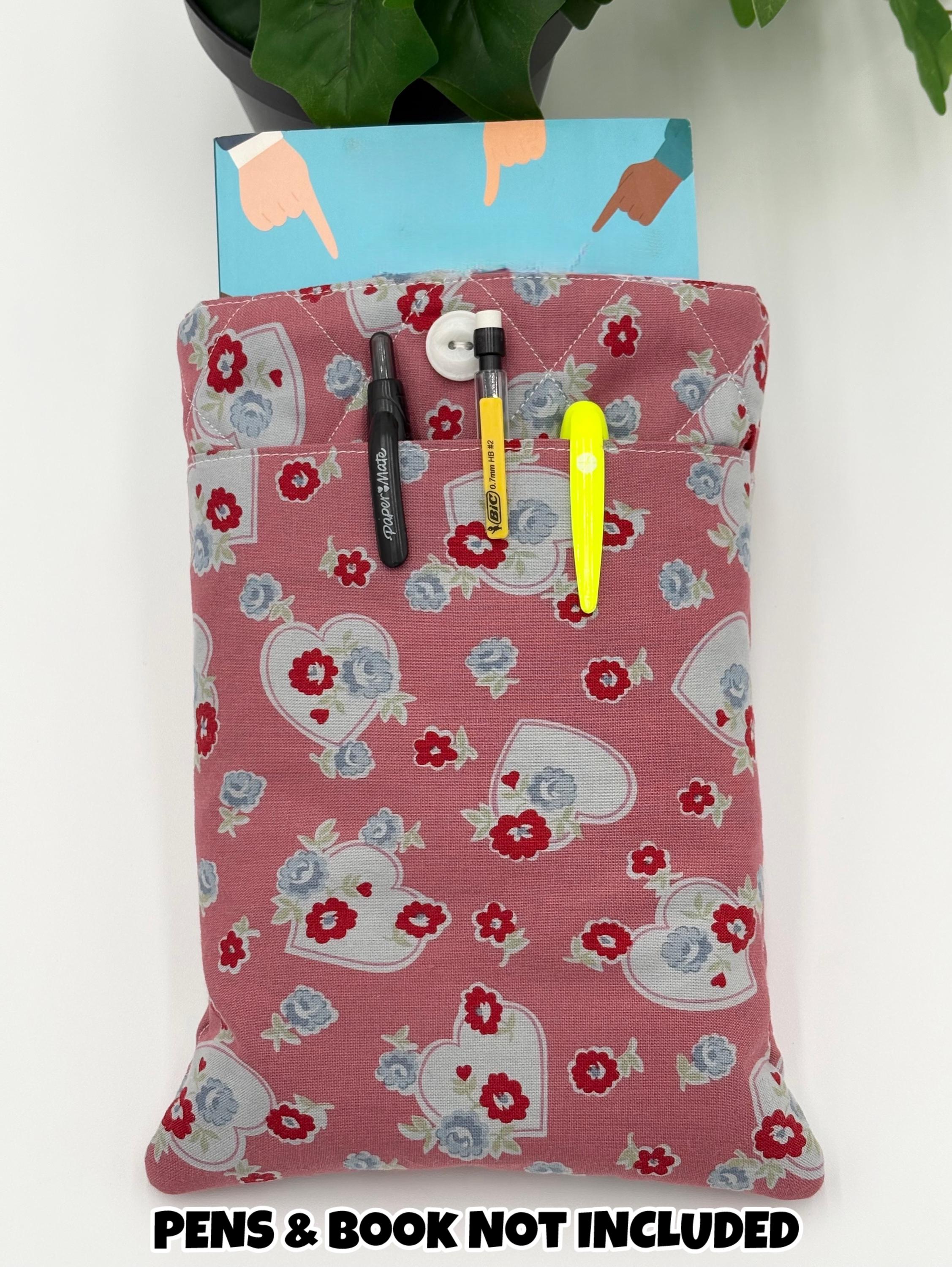Floral and heart patterned book sleeve with pens and book on a white background with the text “pens and book not included”