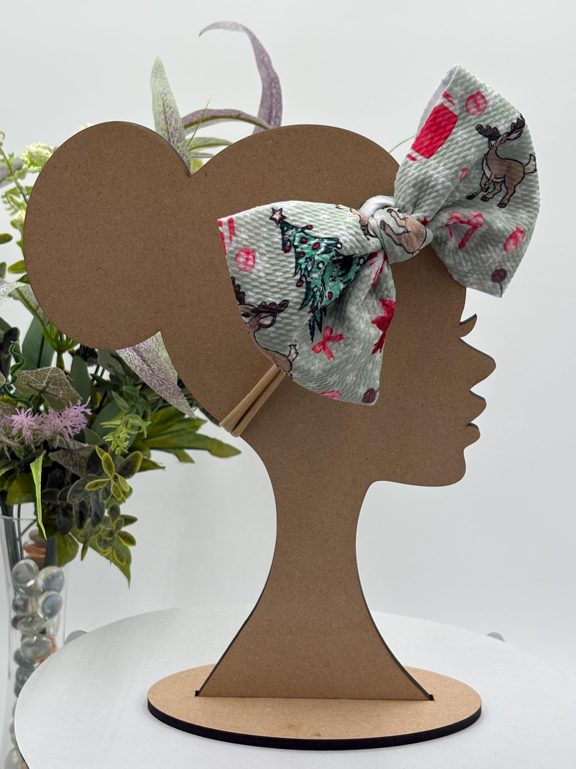 Nylon Headband with a decorative christmas themed big bow on a mannequin head silhouette against a white background